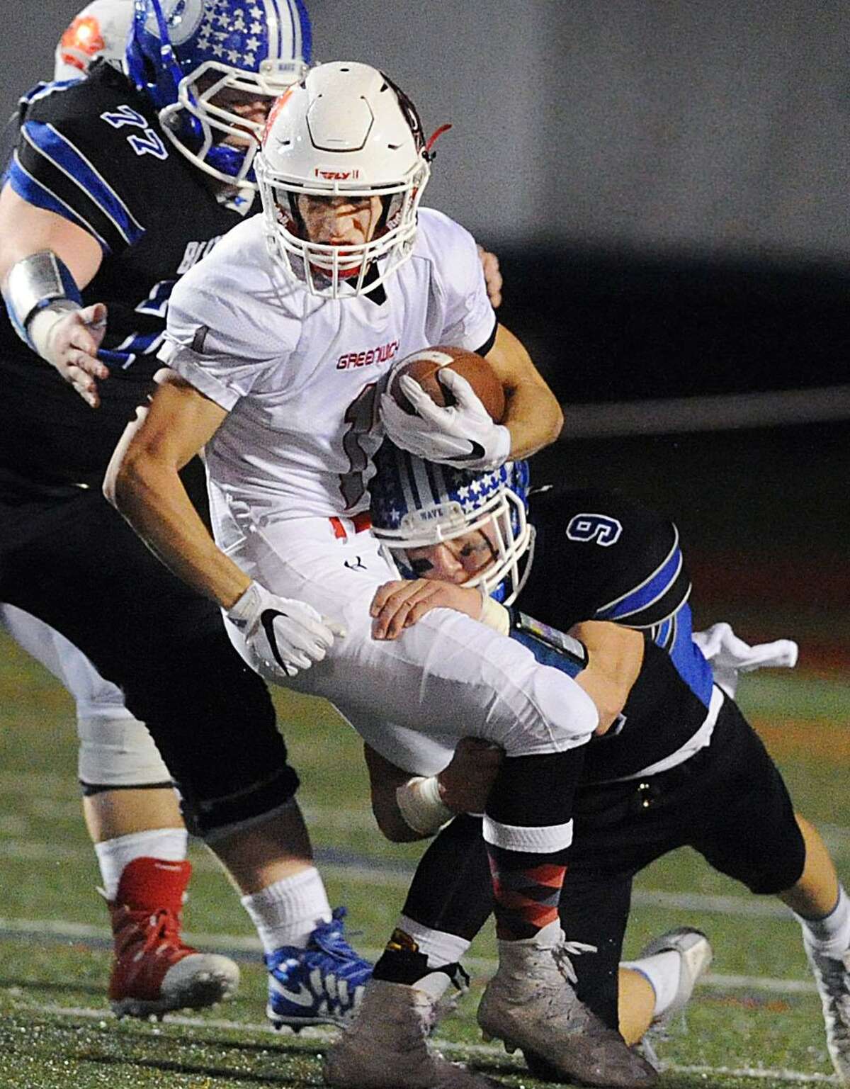 Greeniwch running back Kevin Iobbi (2), center, is tackled by Darien defenders Finlay Collins (9), right, and Justin Plank (77) during the Class LL playoff game between Greenwich and Darien at Stamford High School on Nov. 29. Iobbi was a All-FCIAC First-team selection and helped the Cardinals vastly improve.