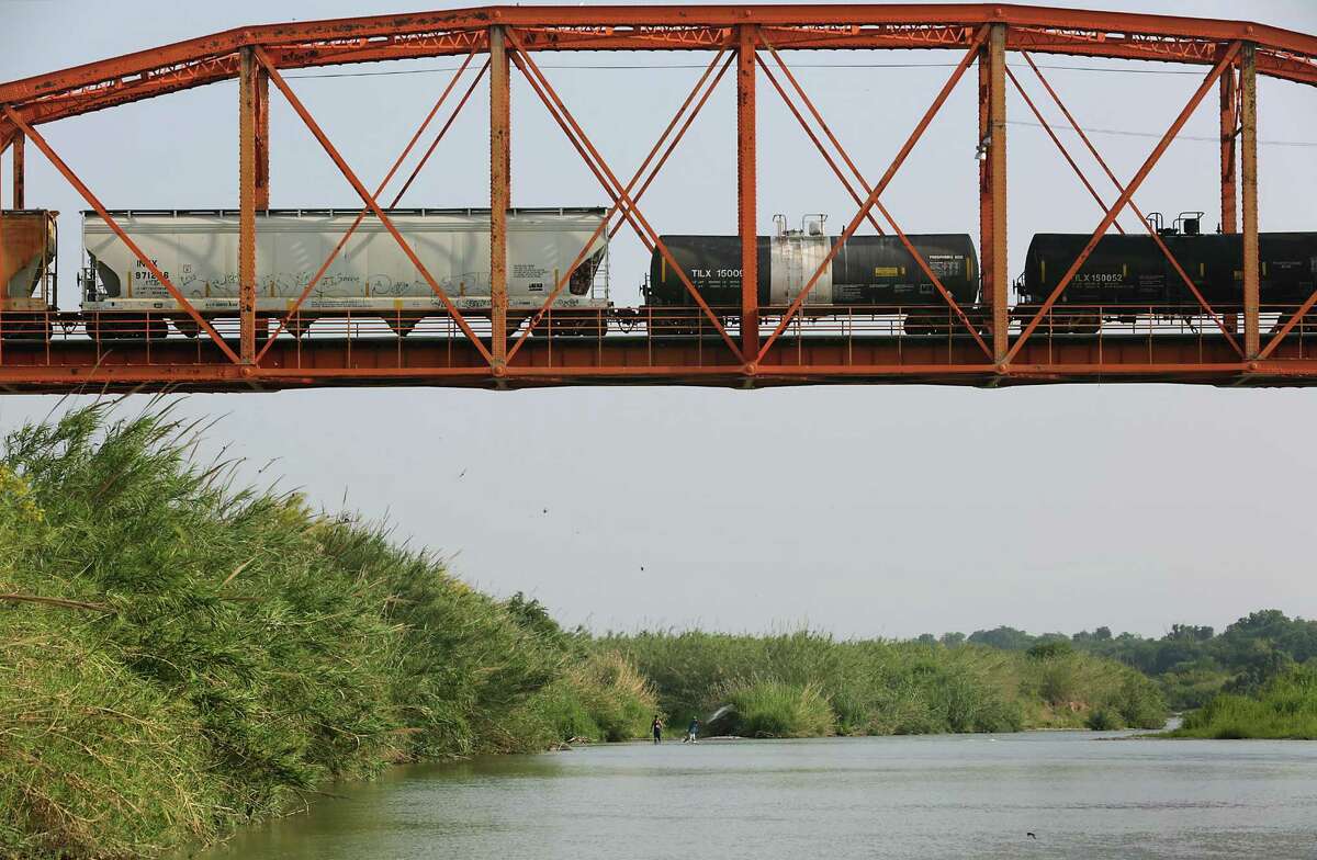 A train crosses the Rio Grande River into Piedras Negras, MX as fishermen cast their nets on Thursday, April 28, 2016.