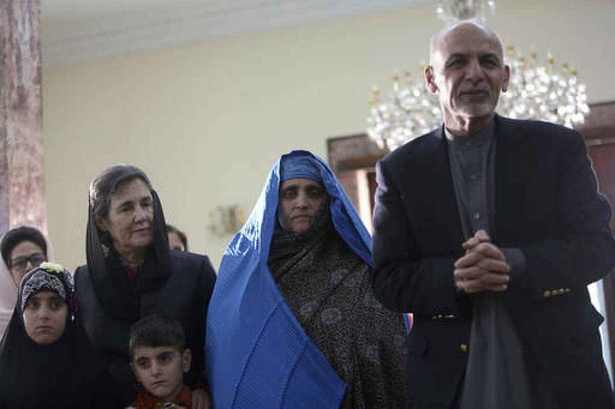 Afghan President Ashraf Ghani, right, meets with National Geographic's famed green-eyed "Afghan Girl" Sharbat Gulla at the Presidential palace in Kabul, Afghanistan, Nov. 9, 2016. Afghanistan's president on Wednesday welcomed home Gulla who was deported from Pakistan after a court had convicted her on charges of carrying a forged Pakistani ID card and staying in the country illegally. (AP Photo/Rahmat Gul)