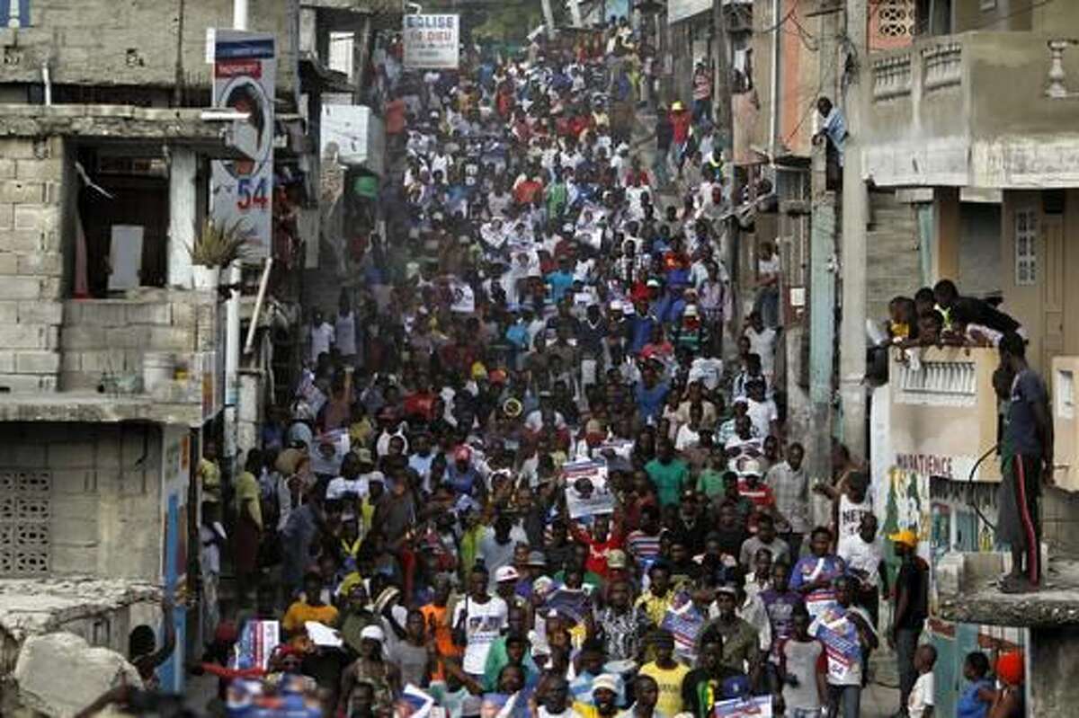 Supporters of presidential candidate Maryse Narcisse from the Fanmi Lavalas political party march through the streets of Port-au-Prince, Haiti, Tuesday, Nov. 22, 2016. For a second straight day, partisans with a Haitian political faction hurled rocks at police and burned tires to demand "fair" election results they insist will put their candidate in the presidency. (AP Photo/Ricardo Arduengo)