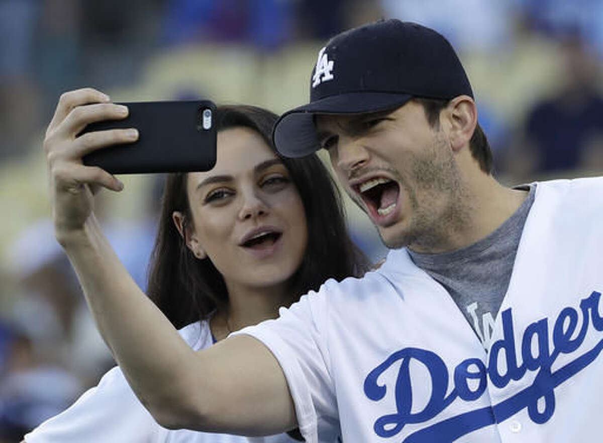 FILE- In this Oct. 19, 2016, file photo, Ashton Kutcher and wife Mila Kunis take a selfie before Game 4 of the National League baseball championship series between the Chicago Cubs and the Los Angeles Dodgers in Los Angeles. Kutcher and Kunis have offered some details on the new addition to their family, a baby boy named Dmitri Portwood Kutcher. Kutcher announced on his website Dec. 2, 2016, that little Dmitri was born at 1:21 a.m. on Nov. 30 and weighed in at 8 pounds, 15 ounces. (AP Photo/David J. Phillip, File)