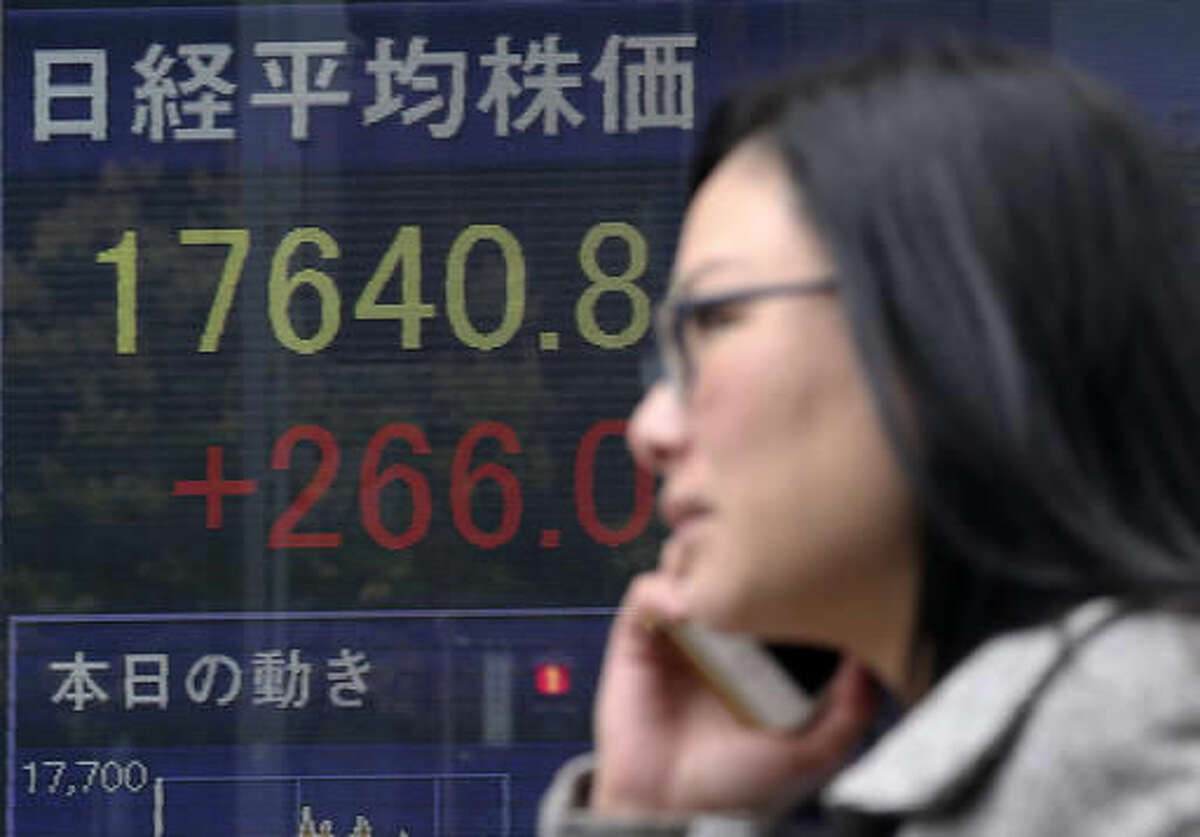A woman walks by an electronic stock board of a securities firm in Tokyo, Monday, Nov. 14, 2016. Asian shares were mostly lower Monday but Japan's benchmark got a boost from a weaker yen. Other regional bourses have gradually steadied after a bout of turmoil following the U.S. presidential election. (AP Photo/Koji Sasahara)