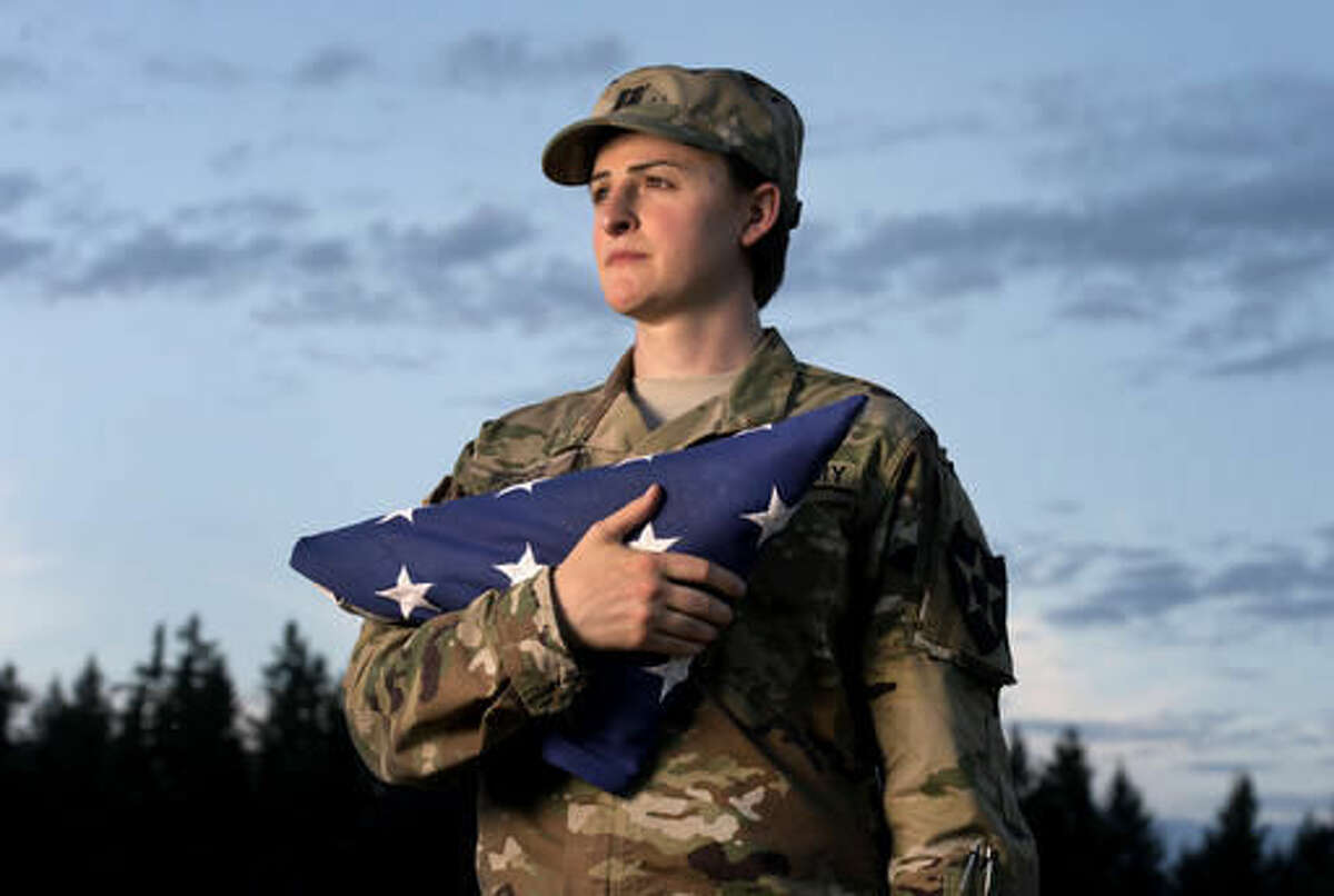 FILE - In this Aug. 28, 2015 file photo, Capt. Jennifer Peace holds a flag as she stands for a photo near her home in Spanaway, Wash. Peace has been been deployed around the world, including Iraq and Afghanistan. When an officer suggested she leave the military rather than deal with the fallout of being a transgender soldier, Peace was taken aback. "I couldn't believe he said that. I've been in the military for 11 years. It's everything to me. It's what I do. It's as much a part of me as anything else." (Drew Perine/The News Tribune via AP)