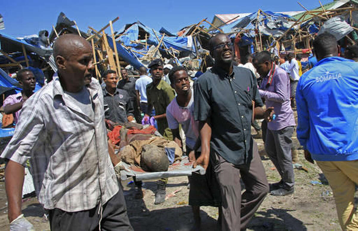 Somali men retrieve the dead body of a person who was killed when a car bomb targeted a police station in the Waberi neighborhood, where President Hassan Sheikh Mohamud was visiting a university, in the capital Mogadishu, Saturday, Nov. 26, 2016. A Somali police official says a car bomb has exploded near a police station in a busy market in the Somali capital, killing a number of people and wounding others. (AP Photo/Farah Abdi Warsameh)