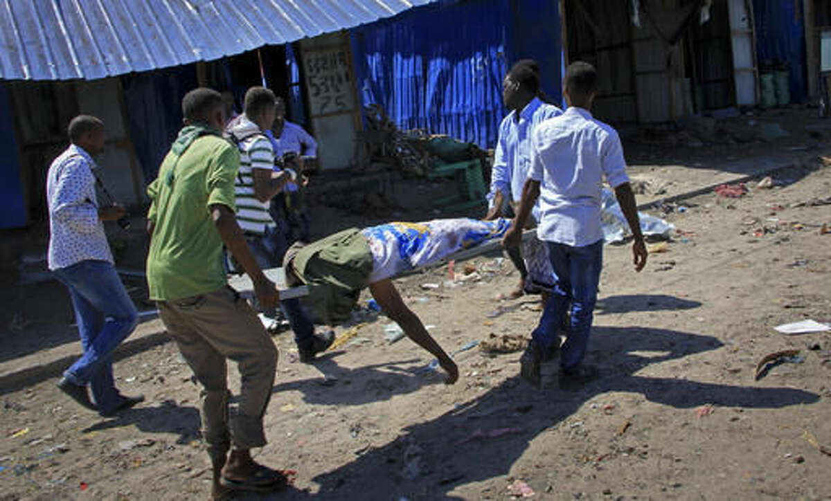 Somali men retrieve the body of a victim killed when a car bomb targeted a police station in the Waberi neighborhood, where President Hassan Sheikh Mohamud was visiting a university, in the capital Mogadishu, Somalia Saturday, Nov. 26, 2016. A Somali police official says a car bomb has exploded near a police station in a busy market in the Somali capital, killing a number of people and wounding others. (AP Photo/Farah Abdi Warsameh)