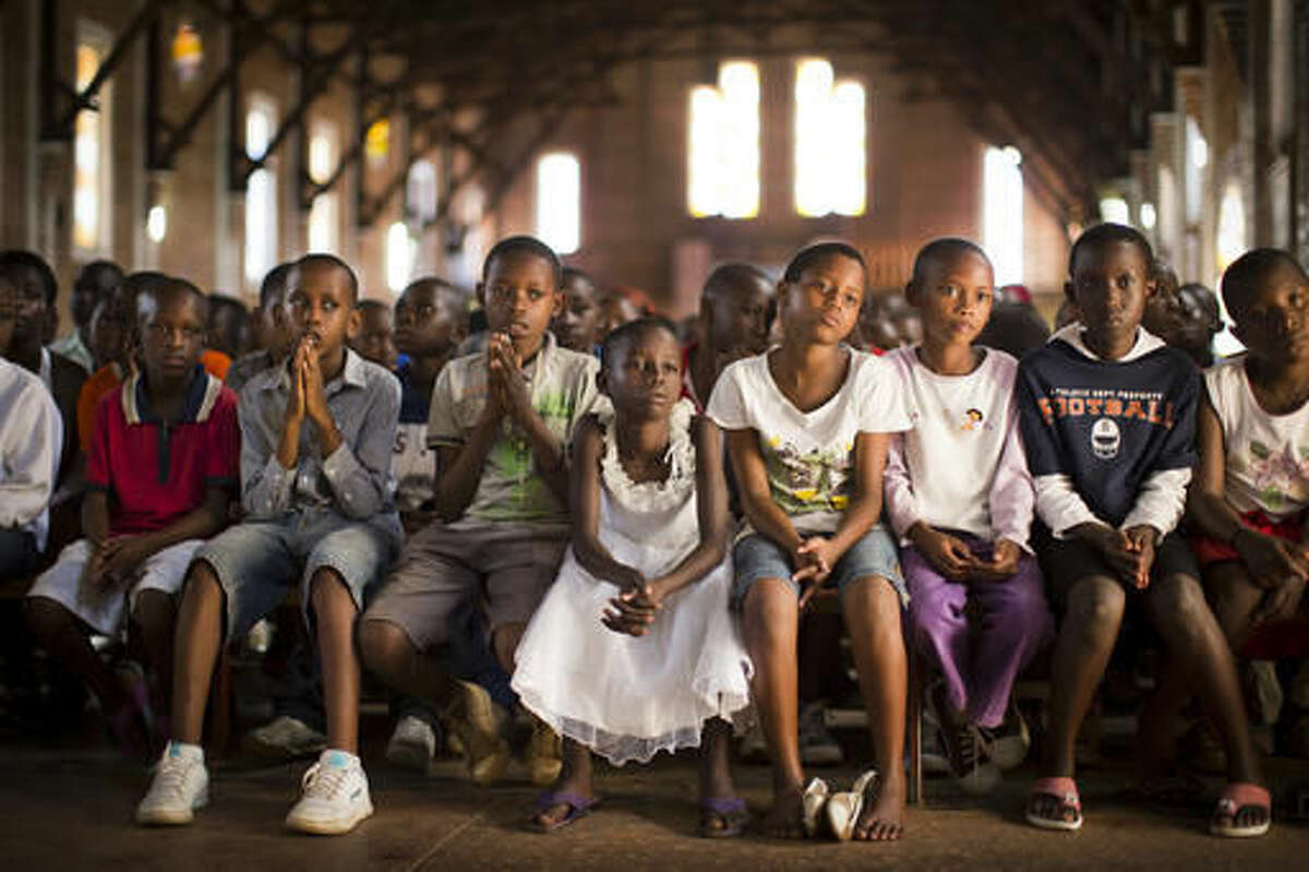 FILE - In this Sunday, April 6, 2014 file photo, Rwandan children listen and pray during a Sunday morning service at the Saint-Famille Catholic church, the scene of many killings during the 1994 genocide, in the capital Kigali, Rwanda. The Catholic Church in Rwanda apologized on Sunday, Nov. 20, 2016, for the church's role in the 1994 genocide, saying it regretted the actions of those who participated in the massacres. (AP Photo/Ben Curtis, File)