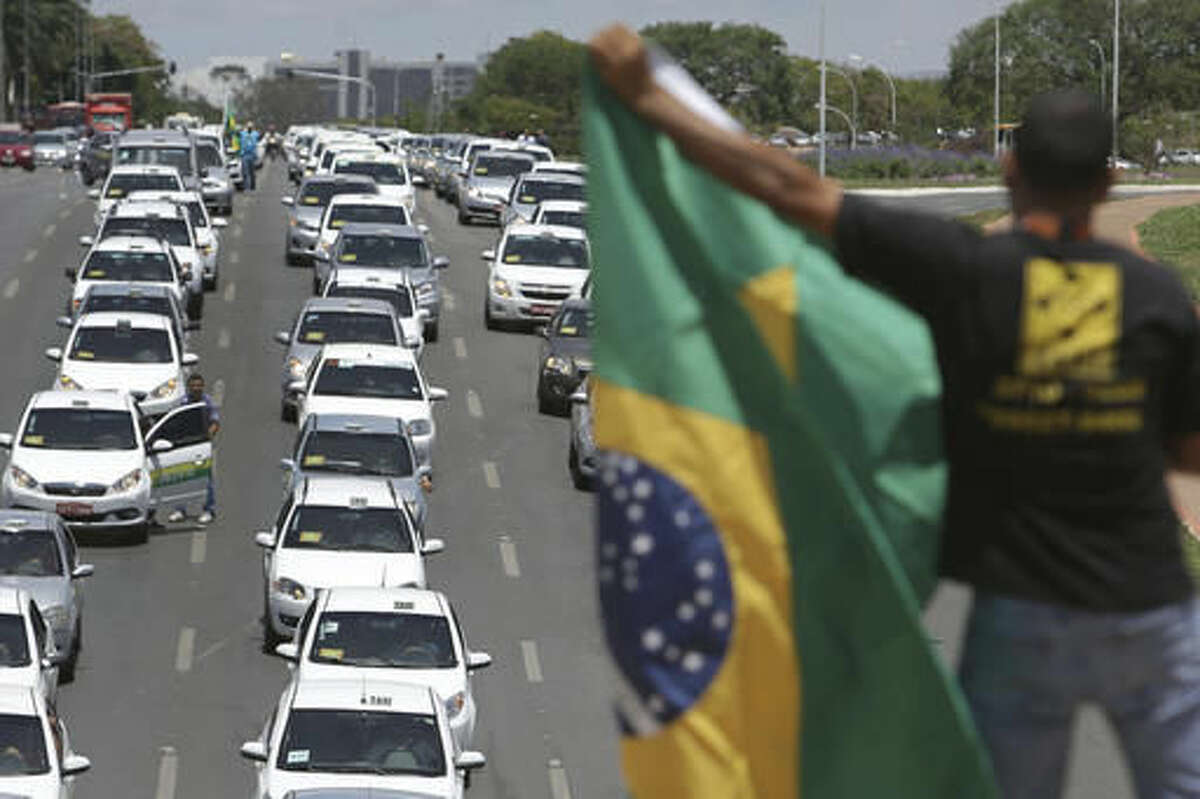Taxi drivers protest against the online transportation service Uber, in Brasilia, Brazil, Tuesday, Nov. 8, 2016. More than one thousand taxi drivers, many in their vehicles, staged a protest in front of Congress demanding that it prohibits the U.S. based company from operating in Latin America's largest nation. (AP Photo/Eraldo Peres)