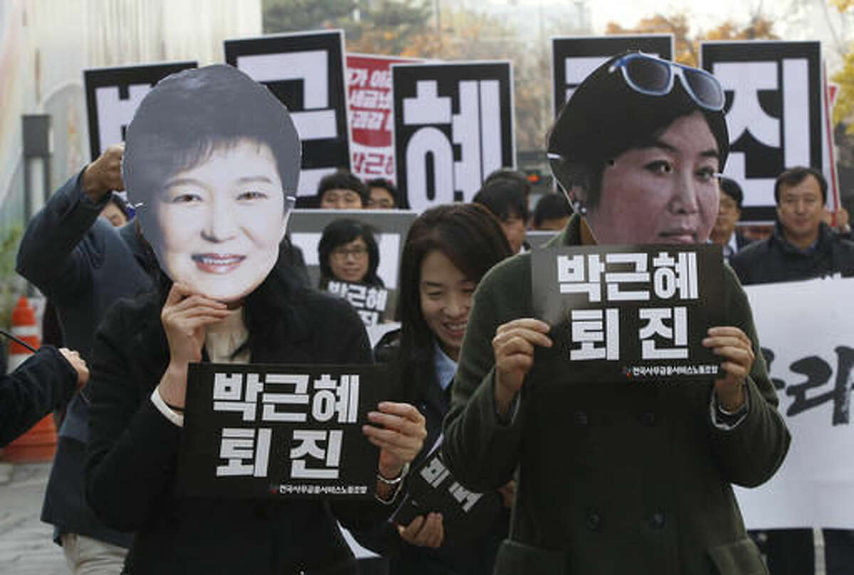 FILE - In this Nov. 18, 2016, file photo, protesters wearing masks of South Korean President Park Geun-hye, left and Choi Soon-sil, Park's longtime friend, in Seoul, South Korea. South Korean prosecutors on Sunday, Nov. 20, 2016, said they believe Park conspired in criminal activities of a secretive confidante who allegedly manipulated government affairs and exploited her presidential ties to amass an illicit fortune - a damning revelation that may convince opposition parties to push for her impeachment. The placards held by the protesters read: "Park Geun-hye should step down." (AP Photo/Ahn Young-joon, File)