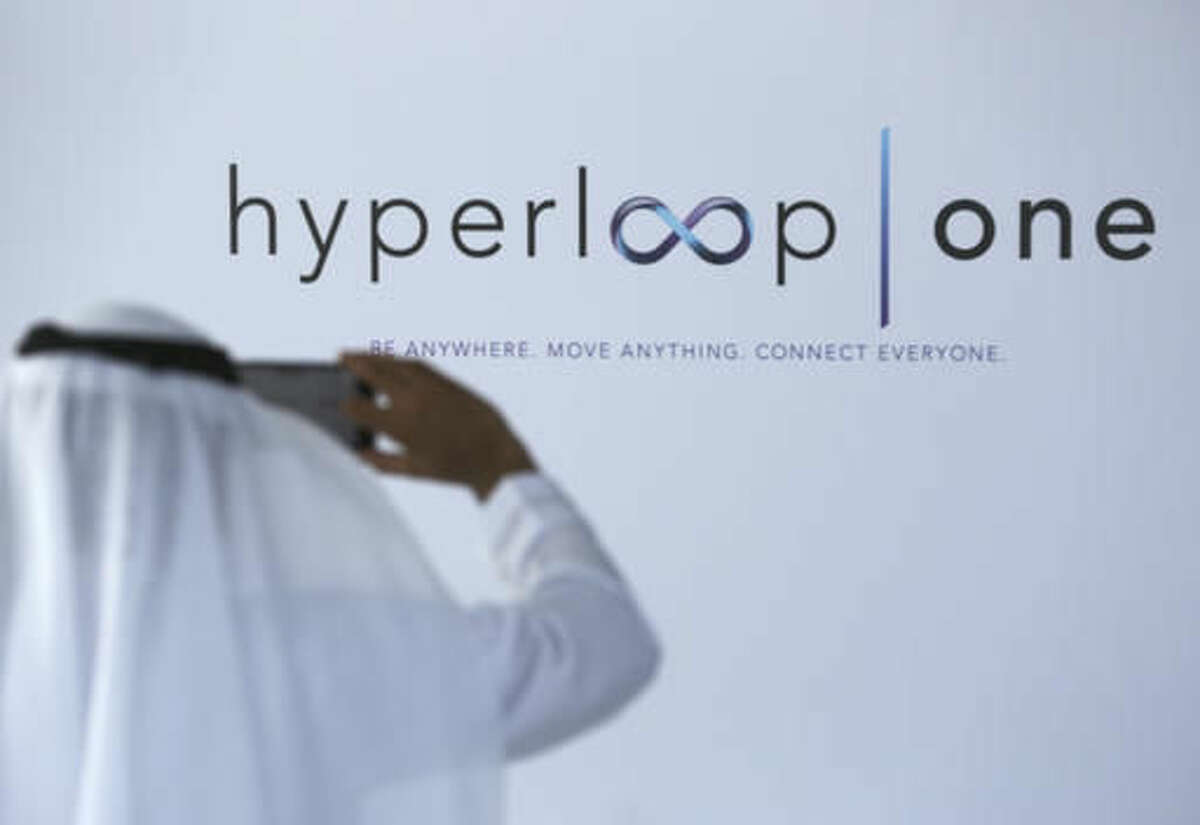 An Emirati takes a photograph of the Hyperloop One logo with his mobile phone in Dubai, United Arab Emirates, Tuesday, Nov. 8, 2016. The futuristic city-state of Dubai announced a deal on Tuesday with Los Angeles-based Hyperloop One to study the potential for building a line linking it to the Emirati capital of Abu Dhabi. (AP Photo/Jon Gambrell)