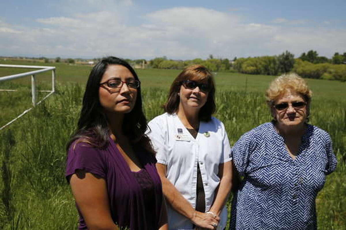 In this May 31, 2016 photo, Nelly Morales, left, Michelle Young, center, and Dawn Stein are photographed on Stein's property, next to a planned oil well complex in Greeley, Colo. Residents of the neighborhood filed a suit against the Colorado Oil and Gas Conservation Commission, alleging the commission didn't enforce rules that would protect residents from some of the impacts of the site. (AP Photo/Brennan Linsley)
