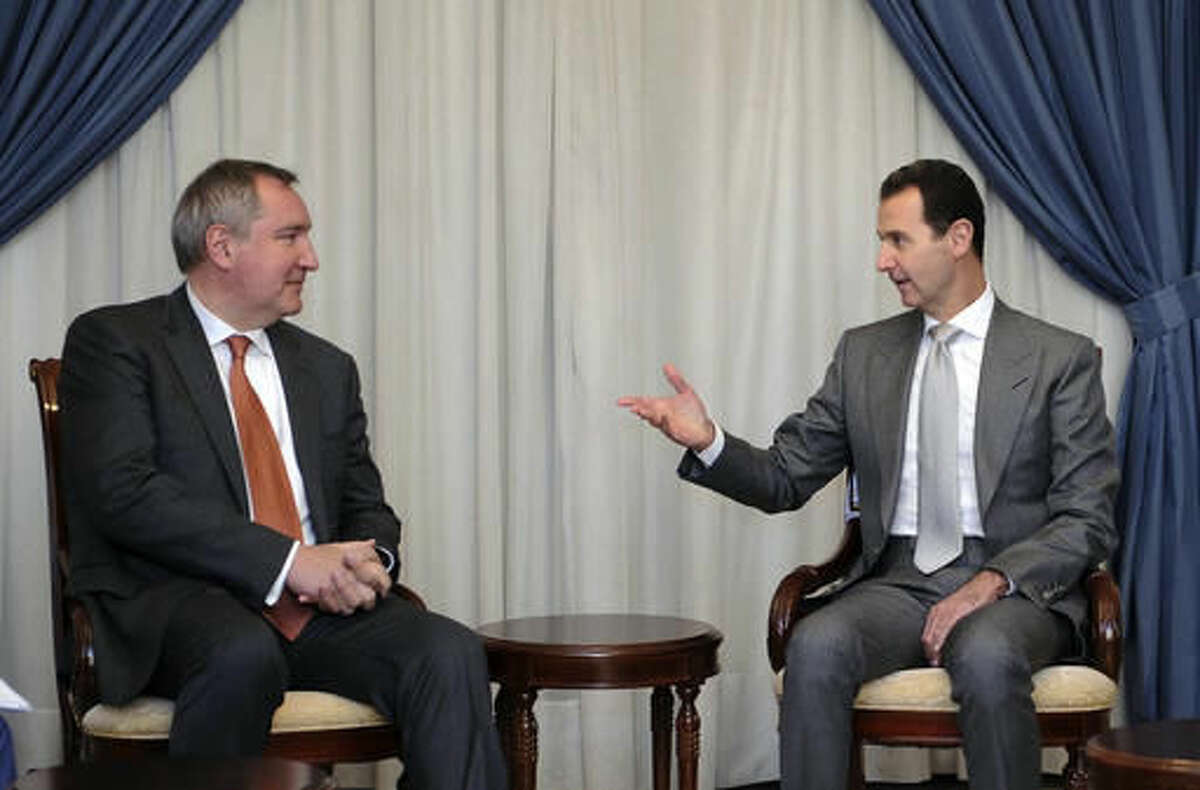 In this photo released by the Syrian official news agency SANA, Syrian President Bashar Assad, right, speaks with Russian Deputy Prime Minister Dmitry Rogozin in Damascus, Syria, Tuesday, Nov. 22, 2016. Russia has backed Assad with vast military support as he fights to put down an uprising that is approaching its sixth year. (SANA via AP)