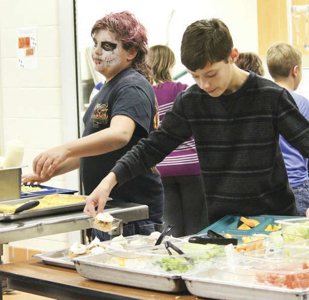 Brandon Rice, right, picks up an apple crisp from the Thermopolis Middle School lunch room. The apple crisp was made from apples picked by students in the farm to school program and served on Halloween. (Tesia Galvan/Northern Wyoming Daily News via aP)
