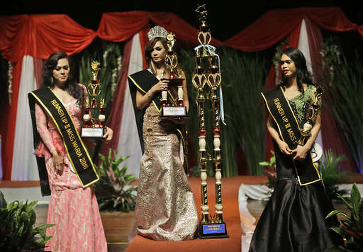 In this Friday, Nov. 11, 2016, photo, Qienabh Tappii, center, holds her trophy as she stands on the stage with first runner up Sefty Castanyo, left, and third place winner Amanda Sandova, right, after winning the Miss Transgender Indonesia pageant in Jakarta, Indonesia. Opposition from Islamic hardliner groups prevented the long-running event twice in recent years as Indonesia's police often look the other way when they attack or intimidate LGBT groups. (AP Photo/Dita Alangkara)
