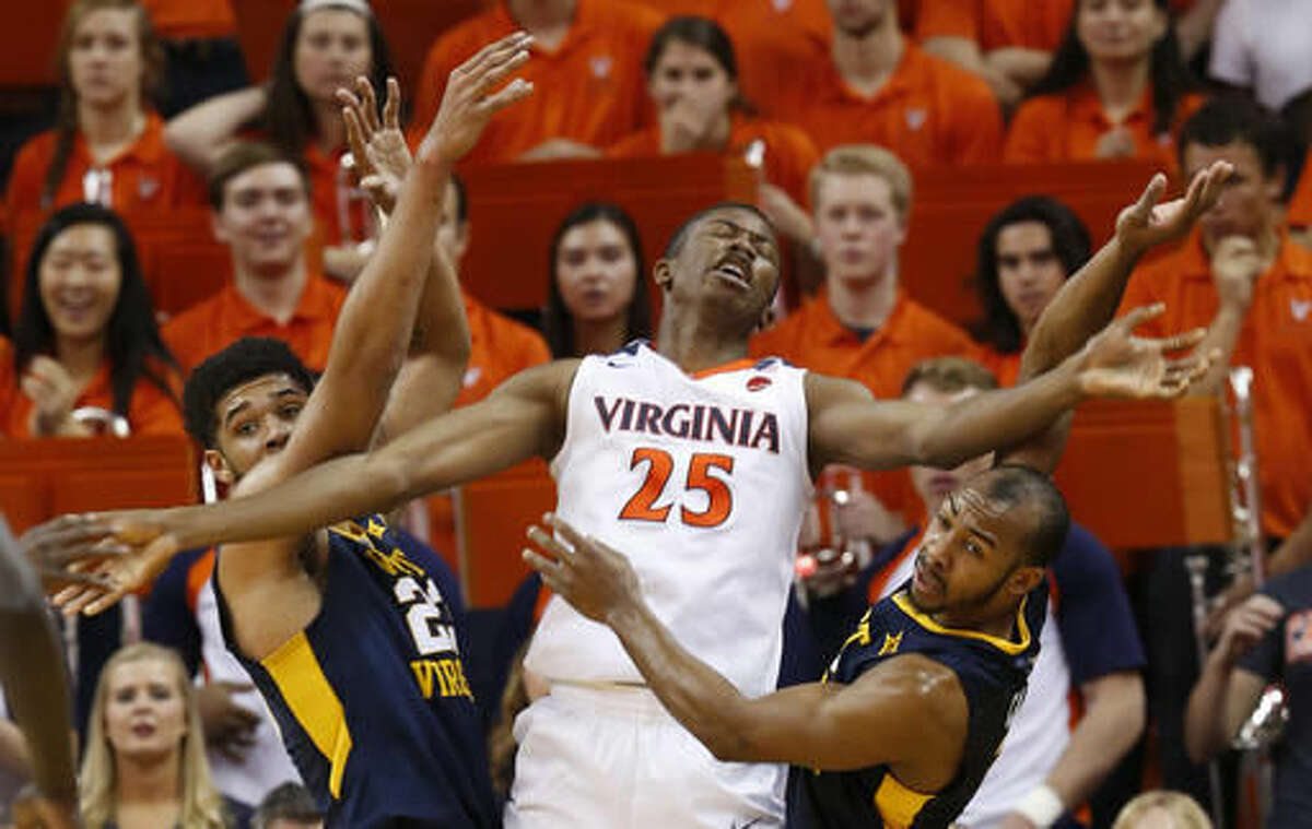 Virginia forward Mamadi Diakite (25) reacts to a foul as West Virginia forward Esa Ahmad (23), left, and West Virginia guard Jevon Carter, right, defend during the first half of an NCAA college basketball game in Charlottesville, Va., Saturday, Dec. 3, 2016. (AP Photo/Steve Helber)