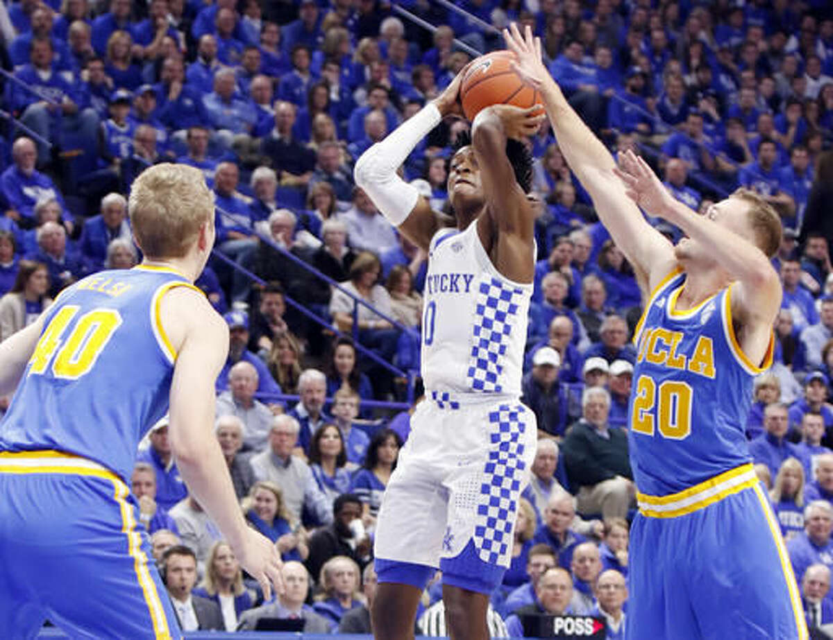 Kentucky's De'Aaron Fox, middle, shoots near the defense of UCLA's Bryce Alford (20) and Thomas Welsh (40) during the first half of an NCAA college basketball game, Saturday, Dec. 3, 2016, in Lexington, Ky. (AP Photo/James Crisp)
