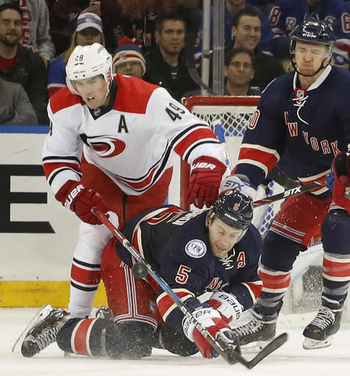 New York Rangers defenseman Dan Girardi (5) hits the ice as he vies for control of the puck against Carolina Hurricanes center Victor Rask (49) during the second period of an NHL hockey game, Saturday, Dec. 3, 2016, in New York. (AP Photo/Julie Jacobson)