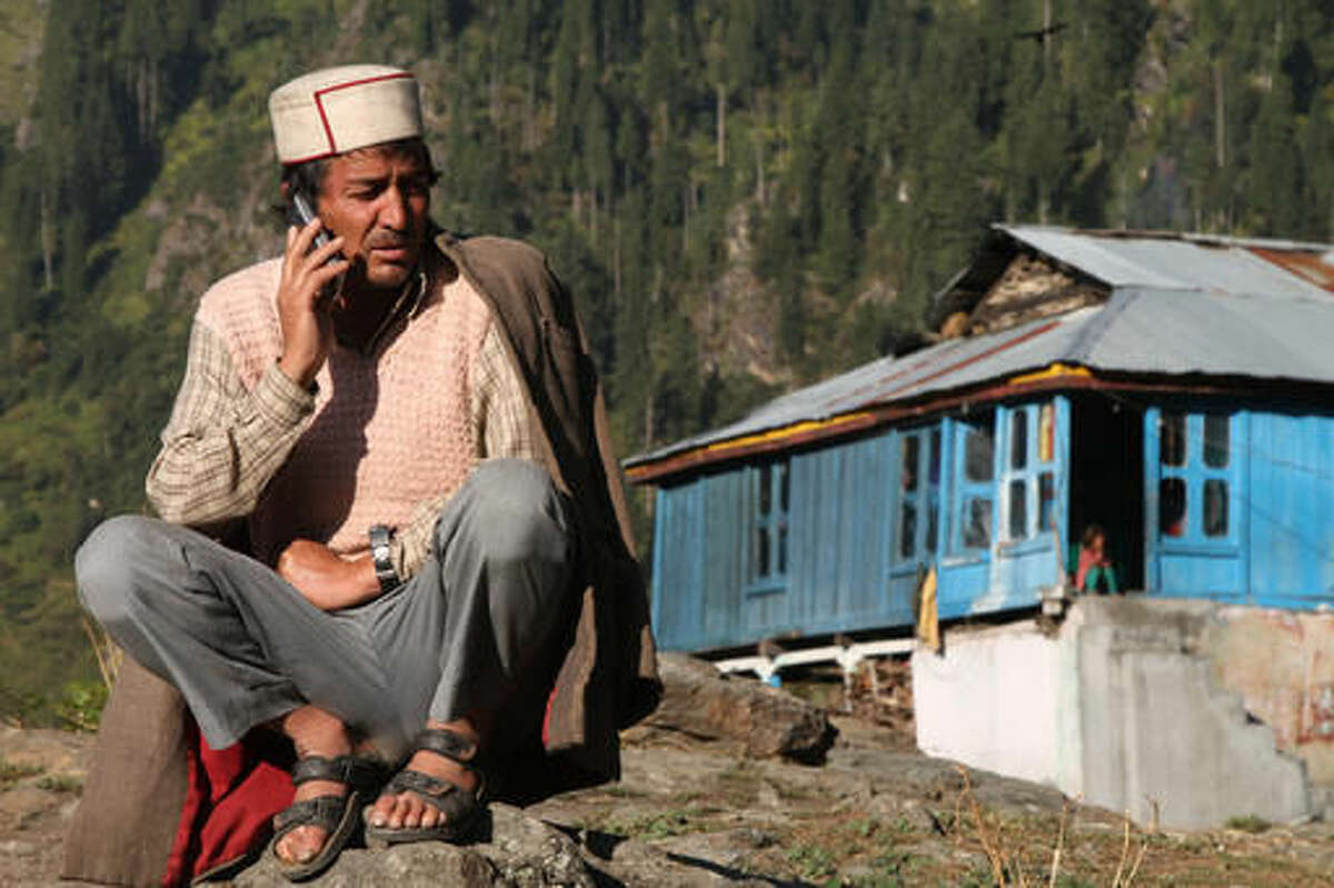In this Tuesday Oct. 4, 2016 photo, Jabe Ram speaks on a mobile phone outside his home on the upper end of Malana village in the northern Indian state of Himachal Pradesh. Malana has become one of the world's top stoner destinations, and a symbolical battleground for India's fight against 'charas,' the black and sticky hashish that has made the village famous. "They want us to completely stop growing marijuana. But we keep sowing it," Ram said. "If the government helped us in some way and protected us from hunger and cold, we would maybe consider stopping. Obviously, we are not going to go hungry. Even if we have to go to jail for it, so be it." (AP Photo/Rishabh R. Jain)