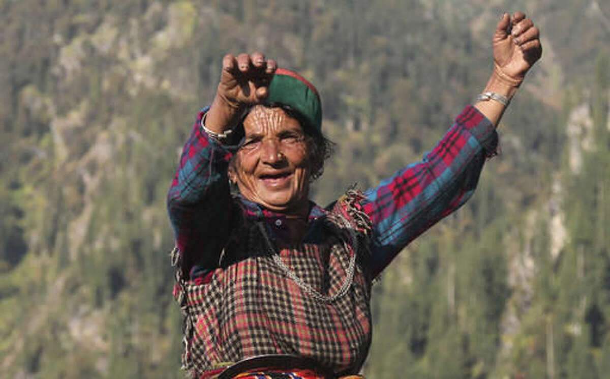 In this Friday, Oct. 7, 2016 photo, Gori Massi sings and dances on the way to work in her cannabis field in Malana village in the northern Indian state of Himachal Pradesh. Every morning, Massi slowly starts the trek to her field, sometimes singing to herself as she walks up a rocky trail. Walking at a pace of a 20-year-old, the wrinkles on her face and hands are the only indication of her age; she is 80. It will take her an hour to get to her plants that are hidden far away from the village near the forest line. She will sit there all day, curing high-potency marijuana buds and rubbing them between her palms to juice out the resin that smears her hands black. (AP Photo/Rishabh R. Jain)