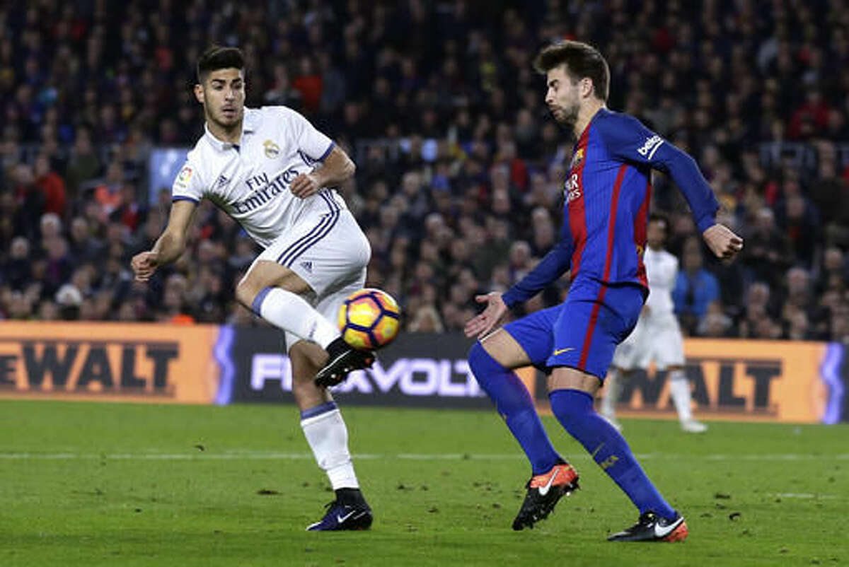 Real Madrid's Marco Asensio, left, goes for the ball with Barcelona's Gerard Pique during the Spanish La Liga soccer match between FC Barcelona and Real Madrid at the Camp Nou in Barcelona, Spain, Saturday, Dec. 3, 2016. (AP Photo/Manu Fernandez)