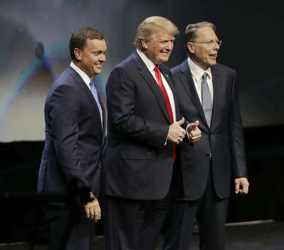 FILE - In this May 20, 2016, file photo, then-Republican presidential candidate Donald Trump is introduced by National Rifle Association executive director Chris W. Cox , left, and NRA executive vice president Wayne LaPierre as he takes the stage to speak at the NRA convention in Louisville, Ky. Firearms enthusiasts who embraced Donald Trump’s presidential campaign and his full-throated support of the Second Amendment are expecting a sweeping expansion of gun rights under his administration and a Congress firmly controlled by Republicans. (AP Photo/Mark Humphrey, File)