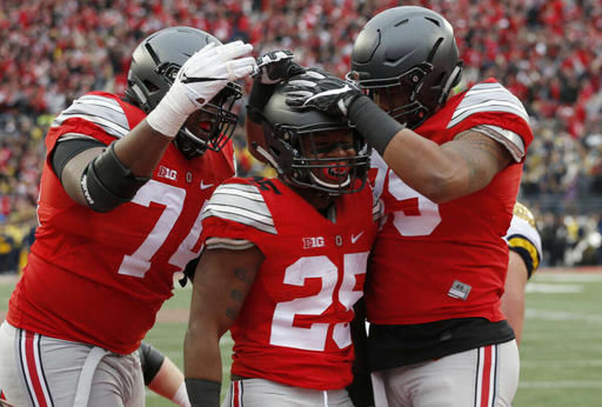 FILE - In this Nov. 26, 2016, file photo, Ohio State running back Mike Weber, center, celebrates his touchdown against Michigan with teammates Jamarco Jones, left, and Luke Farrell during the second half of an NCAA college football game in Columbus, Ohio. Alabama will play Washington and Ohio State is set to face Clemson in the College Football Playoff semifinals, announced Sunday, Dec. 4. (AP Photo/Jay LaPrete)
