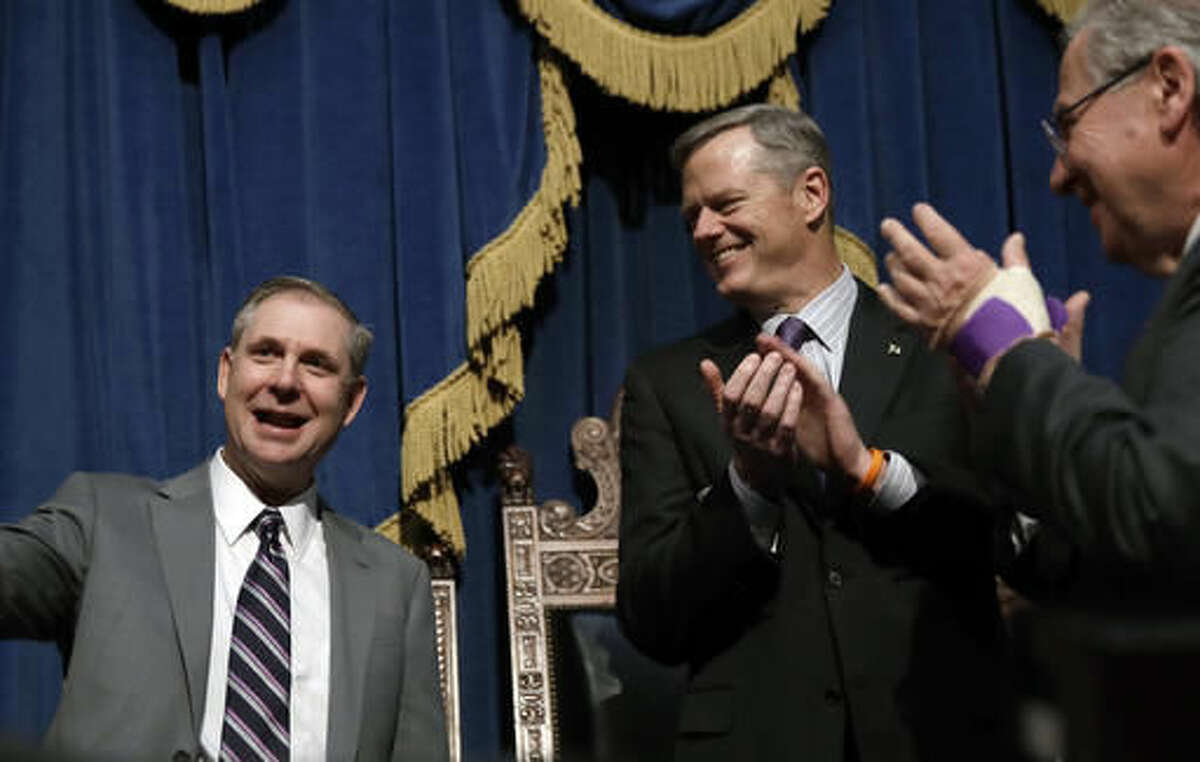Supreme Judicial Court justice David Lowy, left, receives applause by Massachusetts Gov. Charlie Baker, center, and House Speaker Robert DeLeo, right, Friday, Nov. 18, 2016, during his installation ceremony at the Statehouse in Boston. (AP Photo/Charles Krupa)