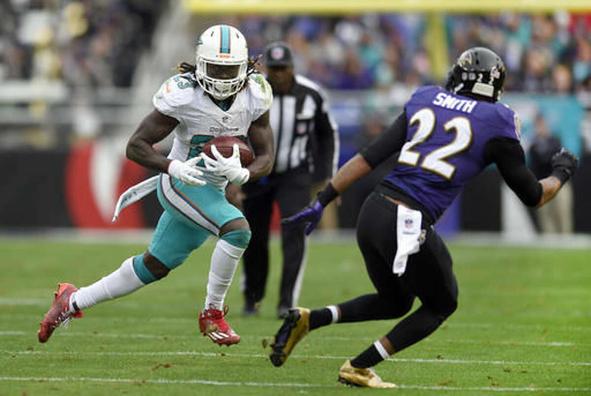 Miami Dolphins running back Jay Ajayi, left, rushes against Baltimore Ravens cornerback Jimmy Smith in the first half of an NFL football game, Sunday, Dec. 4, 2016, in Baltimore. (AP Photo/Nick Wass)