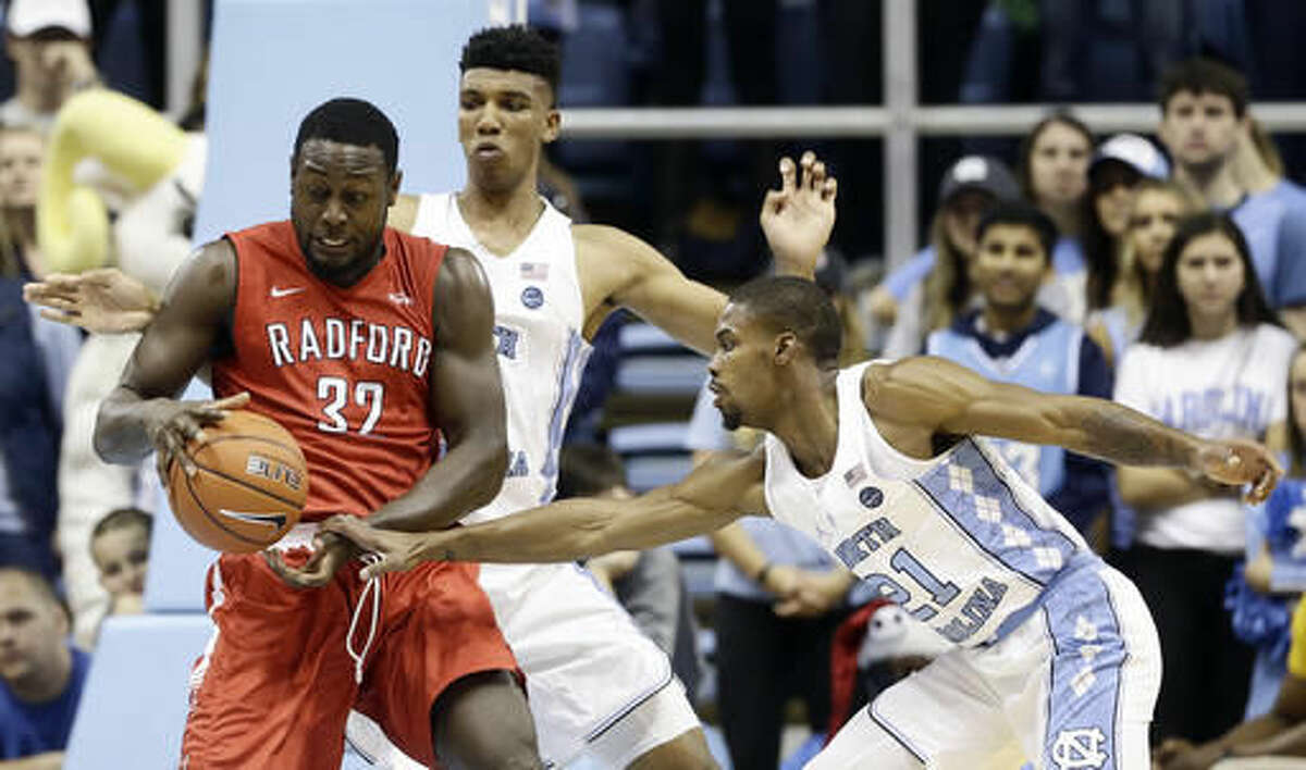 North Carolina's Tony Bradley, rear, and Seventh Woods (21) guard Radford's Randy Phillips (32) during the first half of an NCAA college basketball game in Chapel Hill, N.C., Sunday, Dec. 4, 2016. (AP Photo/Gerry Broome)