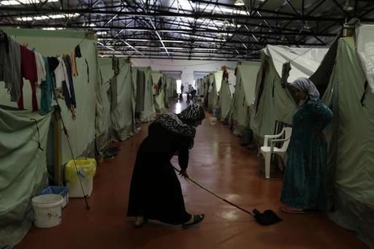 A woman mops the floor outside her tent inside the building of the Kalochori refugee camp, set up in a disused supermarket, on the outskirts of the northern Greek city of Thessaloniki, Tuesday, Nov. 8, 2016. More than 60,000 refugees are stranded in Greece, unable to continue their journeys northward to more prosperous European Union countries after Balkan countries shut down their land borders to refugees earlier this year. (AP Photo/Thanassis Stavrakis)