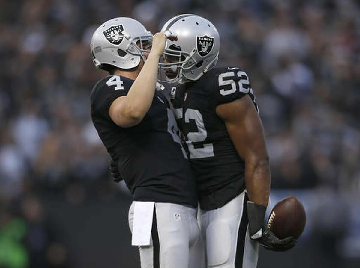 Oakland Raiders quarterback Derek Carr (4) celebrates with defensive end Khalil Mack (52) during the second half of an NFL football game against the Buffalo Bills in Oakland, Calif., Sunday, Dec. 4, 2016. The Raiders won 38-24. (AP Photo/D. Ross Cameron)