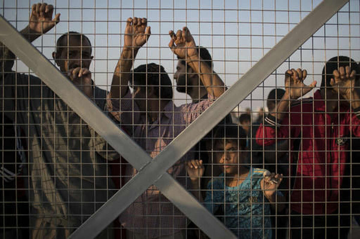 Iraqis displaced by fighting in Mosul line stand behind a fence as food supplies are distributed at a camp for internally displaced people in Hassan Sham, Iraq, on Tuesday, Nov. 8, 2016. The United Nations says over 34,000 people have been displaced from Mosul, with about three quarters settled in camps and the rest in host communities. (AP Photo/Felipe Dana)