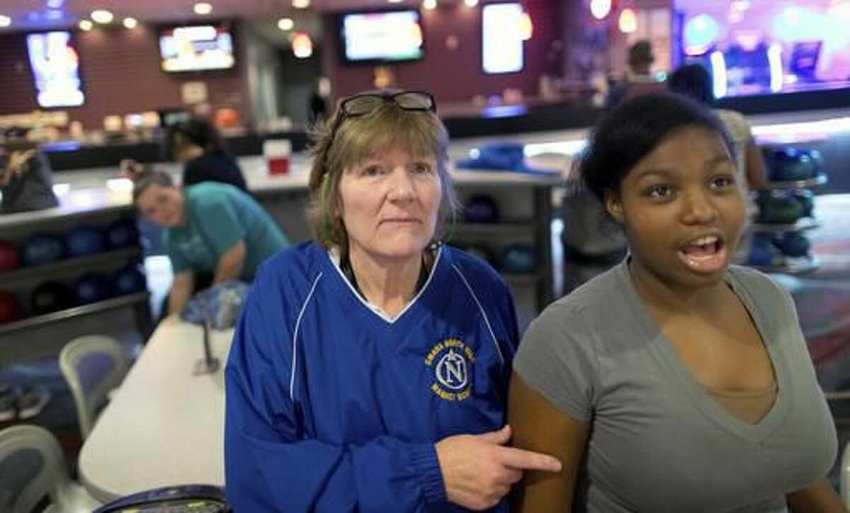 ADVANCE FOR USE SATURDAY, NOV. 19 - In this Tuesday, Nov. 1, 2016 photo, Omaha North High School teacher Lindsey Holley, left, looks at the scoreboard with Jordyn Long-Deal at Maplewood Lanes in Omaha, Neb. It's the first season for North High and more than 40 other high school unified bowling teams across the state.(Matt Miller/Omaha World-Herald via AP)