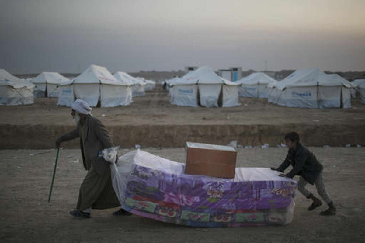 Iraqis displaced by fighting in Mosul carries mattresses at a camp for internally displaced people in Hassan Sham, Iraq, on Tuesday, Nov. 8, 2016. The United Nations says over 34,000 people have been displaced from Mosul, with about three quarters settled in camps and the rest in host communities. (AP Photo/Felipe Dana)