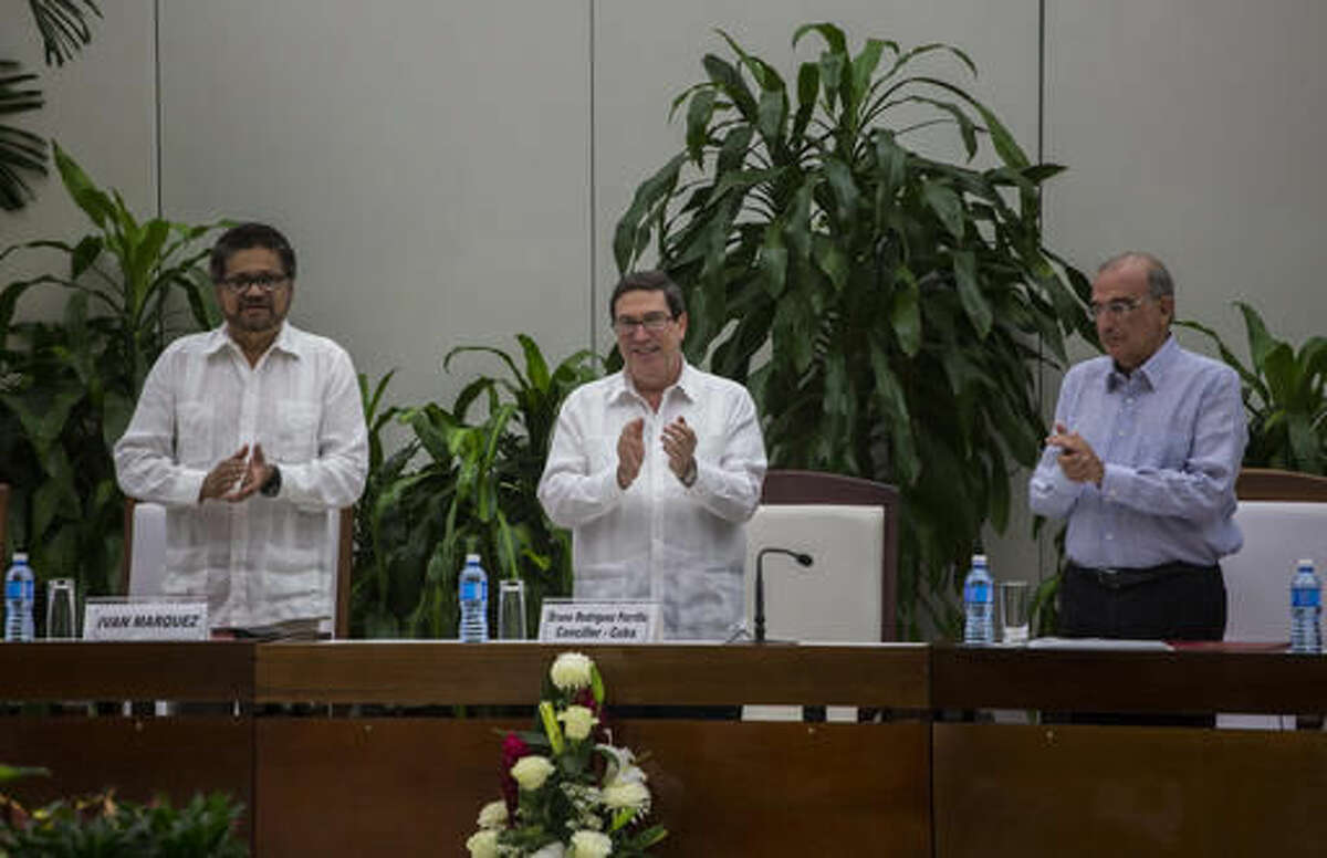 Ivan Marquez, chief negotiator of the Revolutionary Armed Forces of Colombia, or FARC, from left, Cuba's Foreign Minister Bruno Rodriguez, and Humberto de La Calle, head of Colombia's government peace negotiation team, applaud after the signing of the latest text of the peace accord between the two sides in Havana, Cuba, Saturday, Nov. 12, 2016. Colombia's government and the FARC signed a new, modified peace accord on Saturday following the surprise rejection of an earlier deal by voters in a referendum. (AP Photo/Desmond Boylan)
