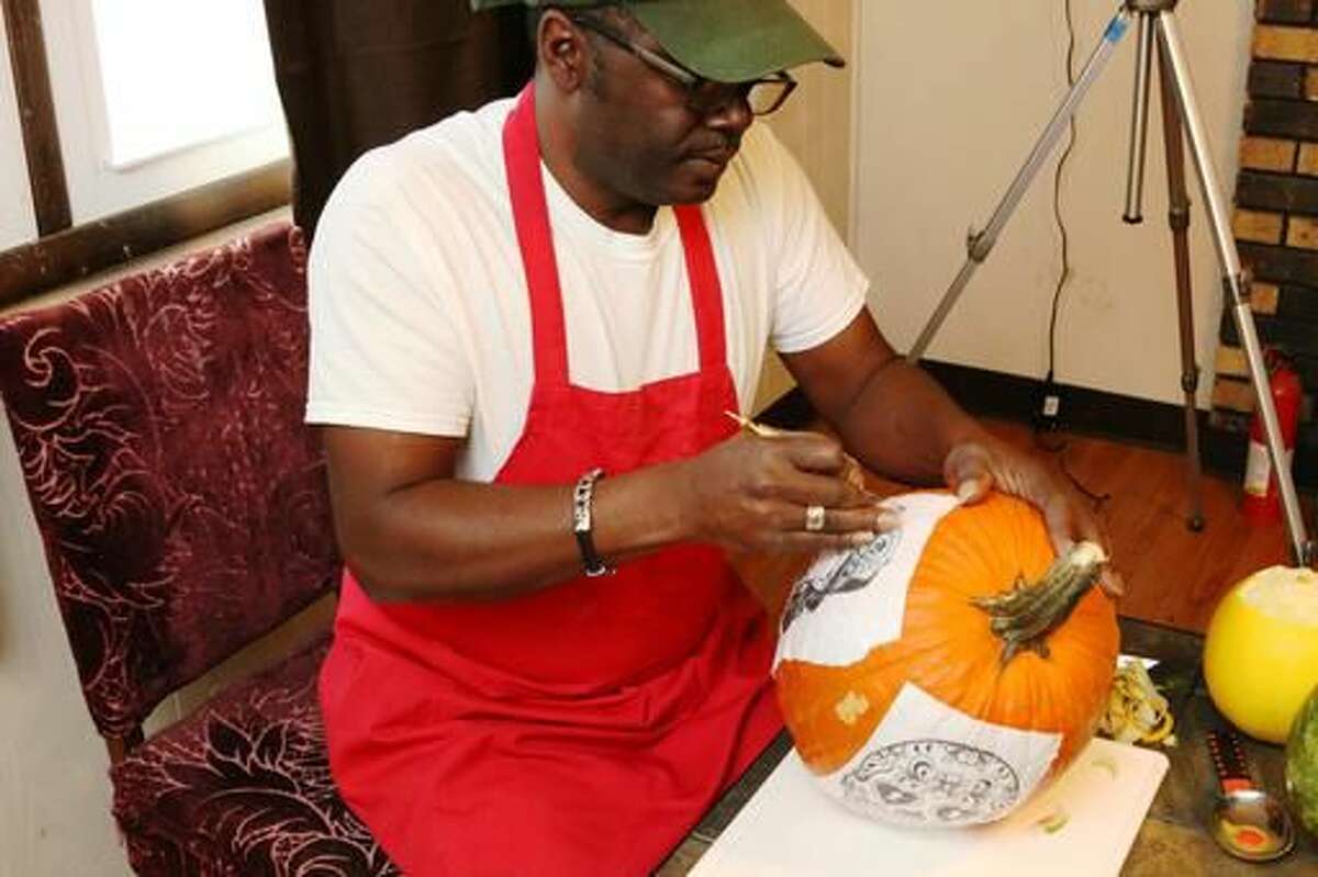 In this Oct. 24, 2016 photo, Fruit carver Lincoln Bias carves a pumpkin with a pattern attached in Rockford, Ill. Bias is an artist, a sculptor, of sorts, whose artwork only remains in photographs and in the memories of the people who are lucky enough to catch a glimpse. Bias, who has lived off and on in Rockford for the past 10 years, carves his masterpieces in fruit, vegetables, garnishes and even soap. (Maggie Hradecky/Rockford Register Star via AP)
