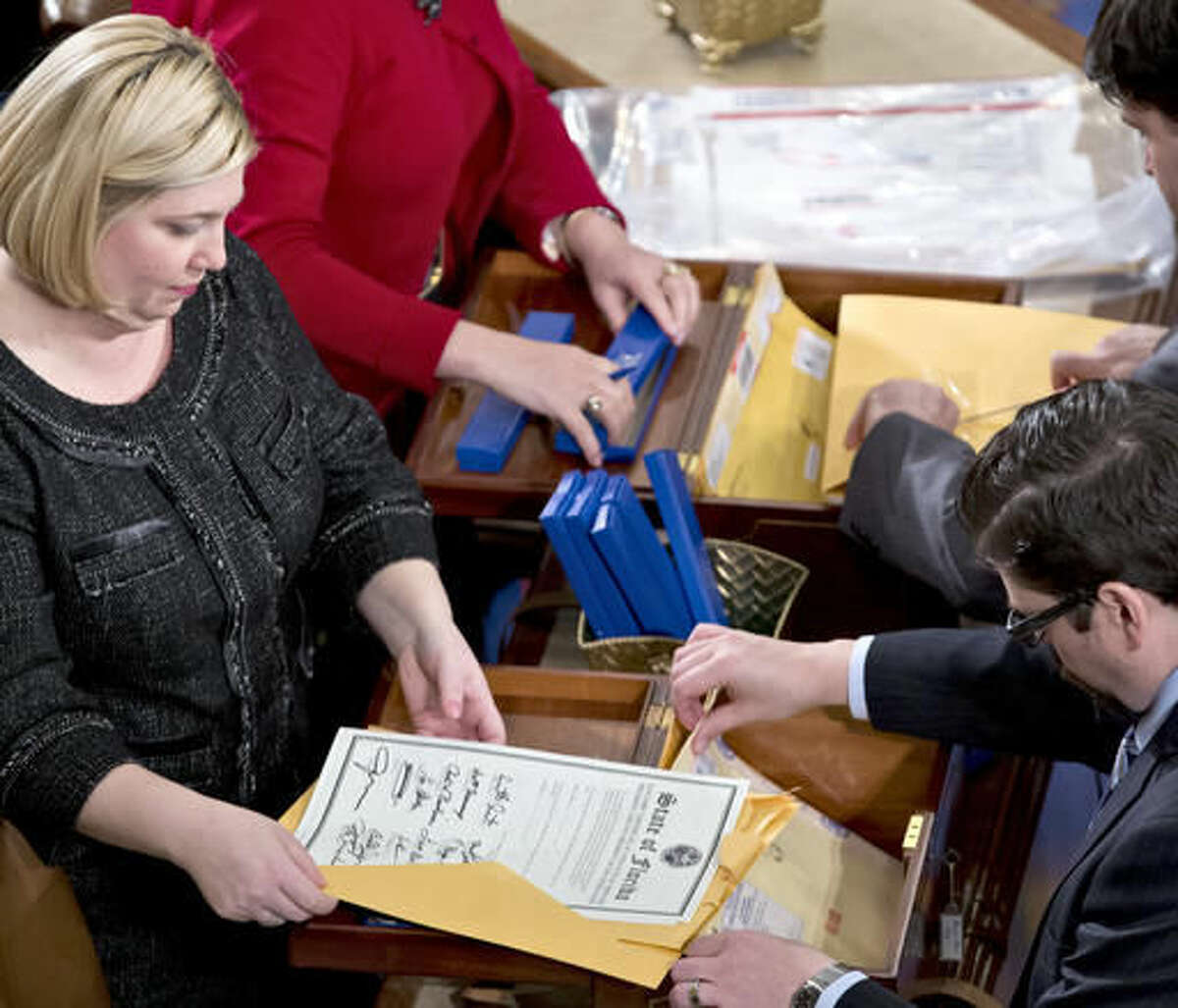 FILE - In this Jan. 4, 2013 file photo, clerks unseal the certificates of results from all fifty states during a meeting of the U.S. Electoral College in the House of Representatives on Capitol in Washington. The Electoral College was devised at the Constitutional Convention in 1787. It was a compromise meant to strike a balance between those who wanted popular elections for president and those who wanted no public input. (AP Photo/J. Scott Applewhite, File)