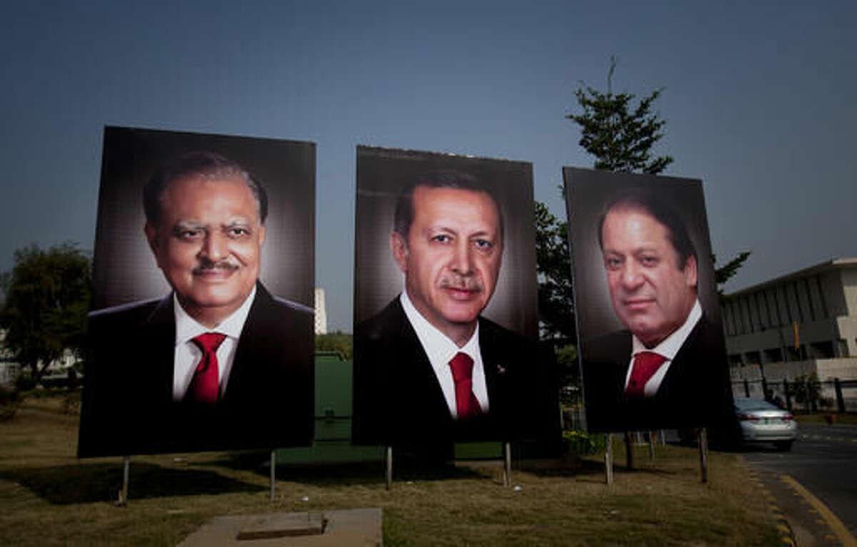 A police officer checks a car at a checkpoint next to billboards showing the portraits of Turkish President Recep Tayyip Erdogan, center, Pakistani President Mamnoon Hussain, left, and Prime Minister Nawaz Sharif, right, welcome Erdogan to Islamabad, Pakistan, Wednesday, Nov. 16, 2016. (AP Photo/Anjum Naveed)