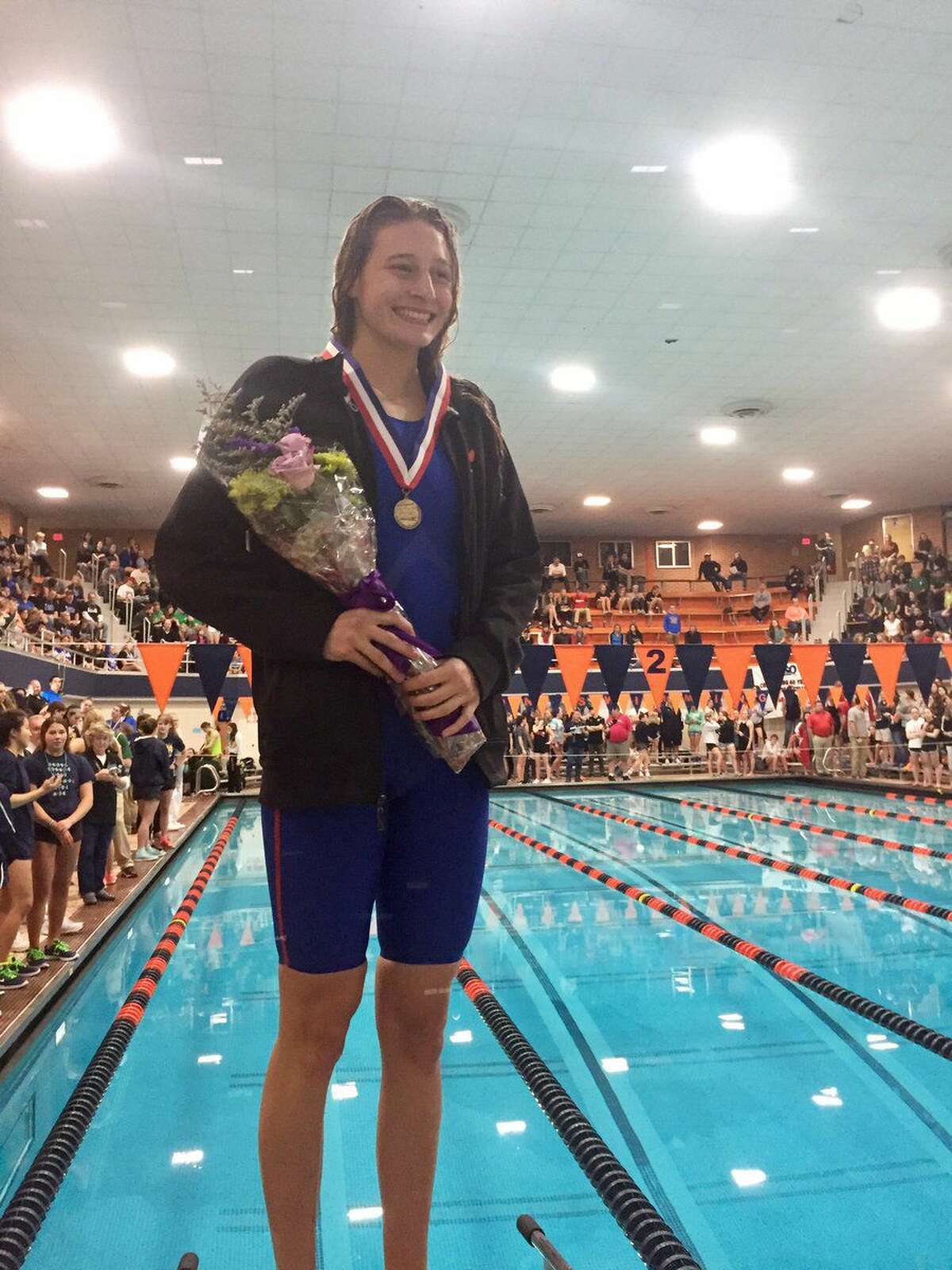 Edwardsville senior Bailey Grinter smiles on the medal stand on Saturday after winning the 100-yard backstroke at the state meet at Evanston High School.