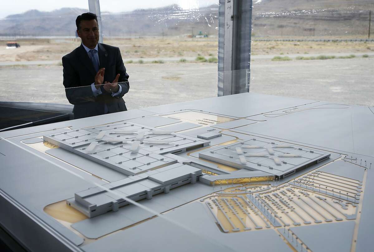 FILE - In this April 13, 2016, file photo, Nevada Gov. Brian Sandoval looks at a model for a Faraday Future factory in North Las Vegas, Nev. Work has stopped at a site outside Las Vegas where upstart electric car company Faraday Future has said it plans to have vehicles that are still in the design phase rolling off a new $1 billion assembly line in 2018. Faraday Future spokesman Ezekiel Wheeler said Tuesday, Nov. 15, 2016, the pause after millions of dollars' worth of ground work at the Apex Industrial Park site will let the company put money and attention toward developing the concept car it wants to present at the big Consumer Electronics Show in Las Vegas in January. (AP Photo/John Locher, File)
