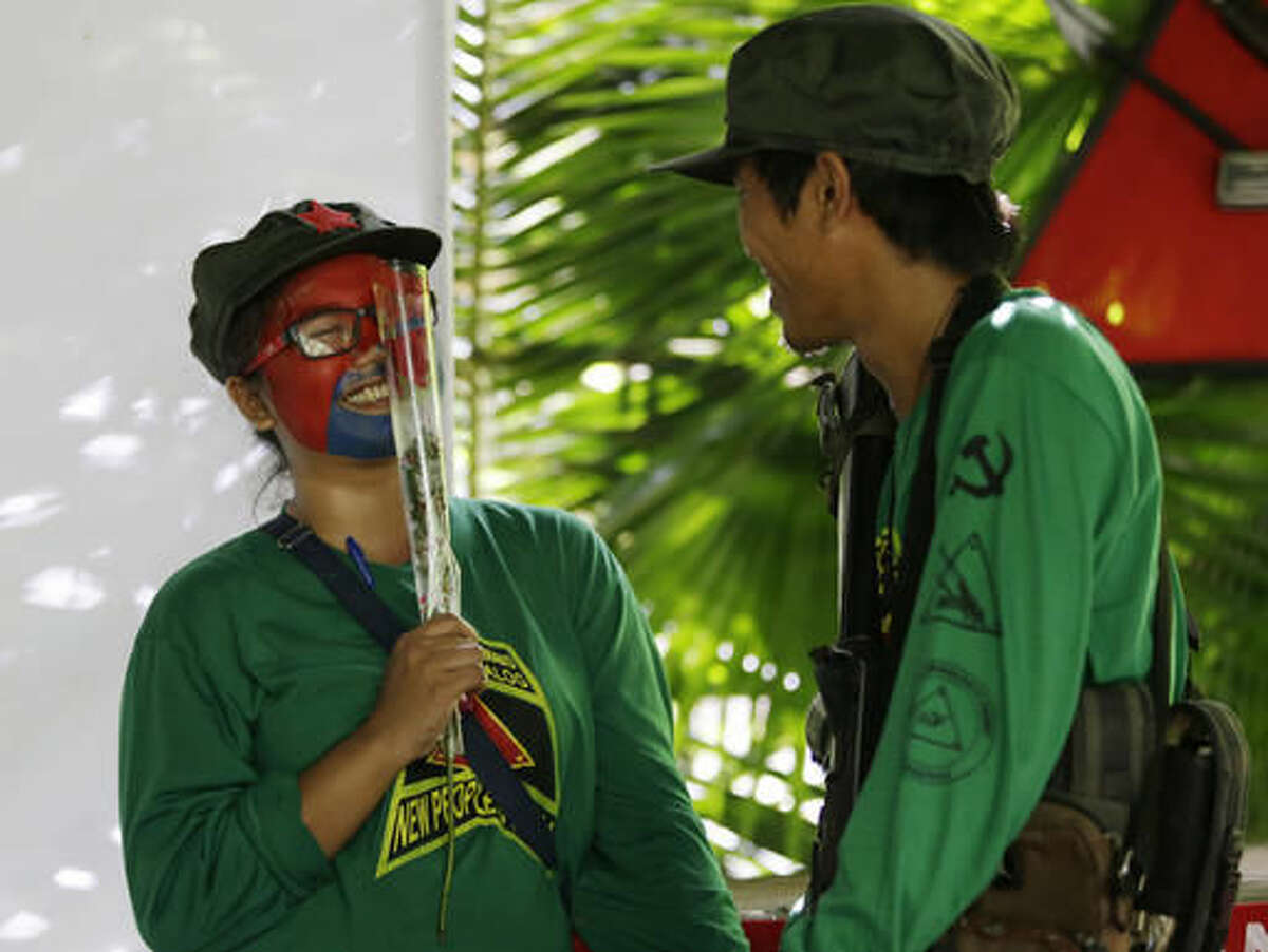 In this Nov. 23, 2016 photo, a New People's Army guerrilla with face painted to conceal their identities gestures after receiving a rose from another guerrilla at their rebel encampment tucked in the harsh wilderness of the Sierra Madre mountains southeast of Manila, Philippines. Young Filipino rebels represent a new generation of Maoist fighters, who reflect the resiliency and constraints of an insurgency that has dragged on for nearly half a century through six Philippine presidencies. Crushing poverty, despair, government misrule and the abysmal inequality that has long plagued Philippine society were their best recruiter, according to the guerrillas. (AP Photo/Aaron Favila)