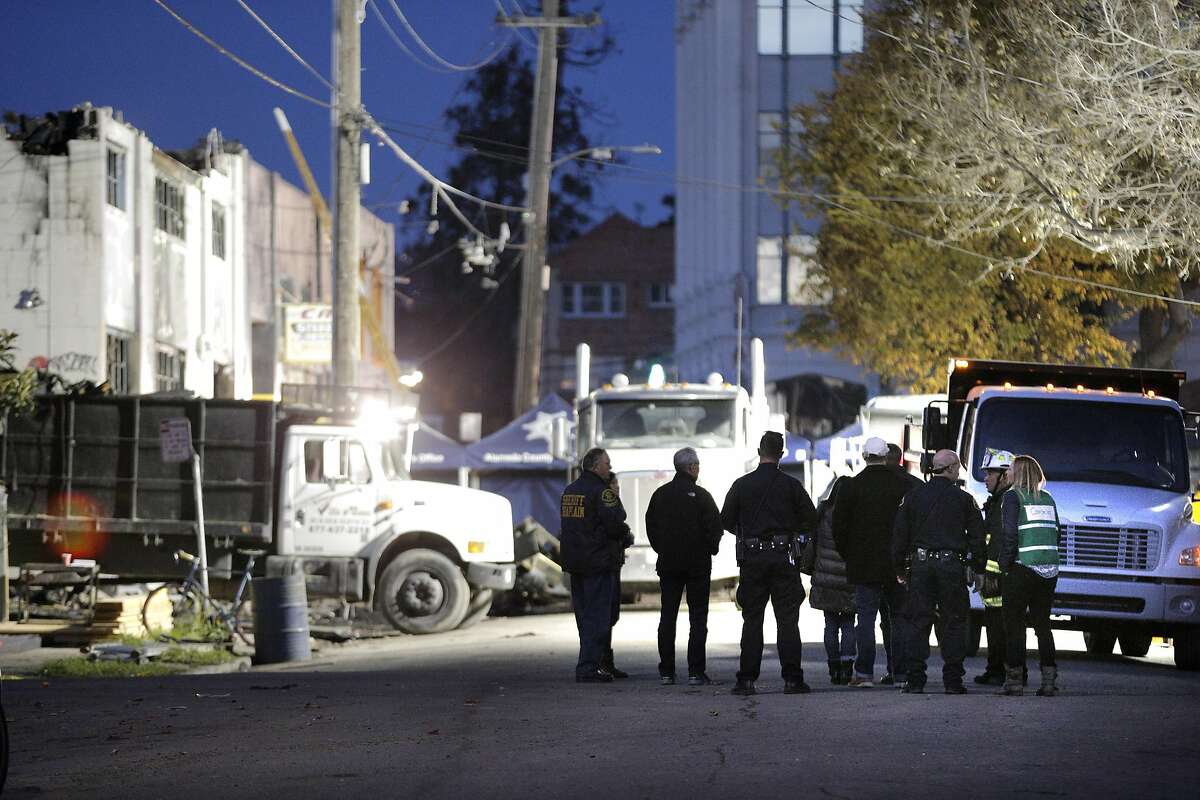 Alameda County Sherrifs and Oakland Fire Department officials escort a victim's family members to the burned out warehouse as recovery efforts came to a close following the Ghost Ship fire that claimed 36 lives in Oakland, Calif., on Tuesday, December 6, 2016.