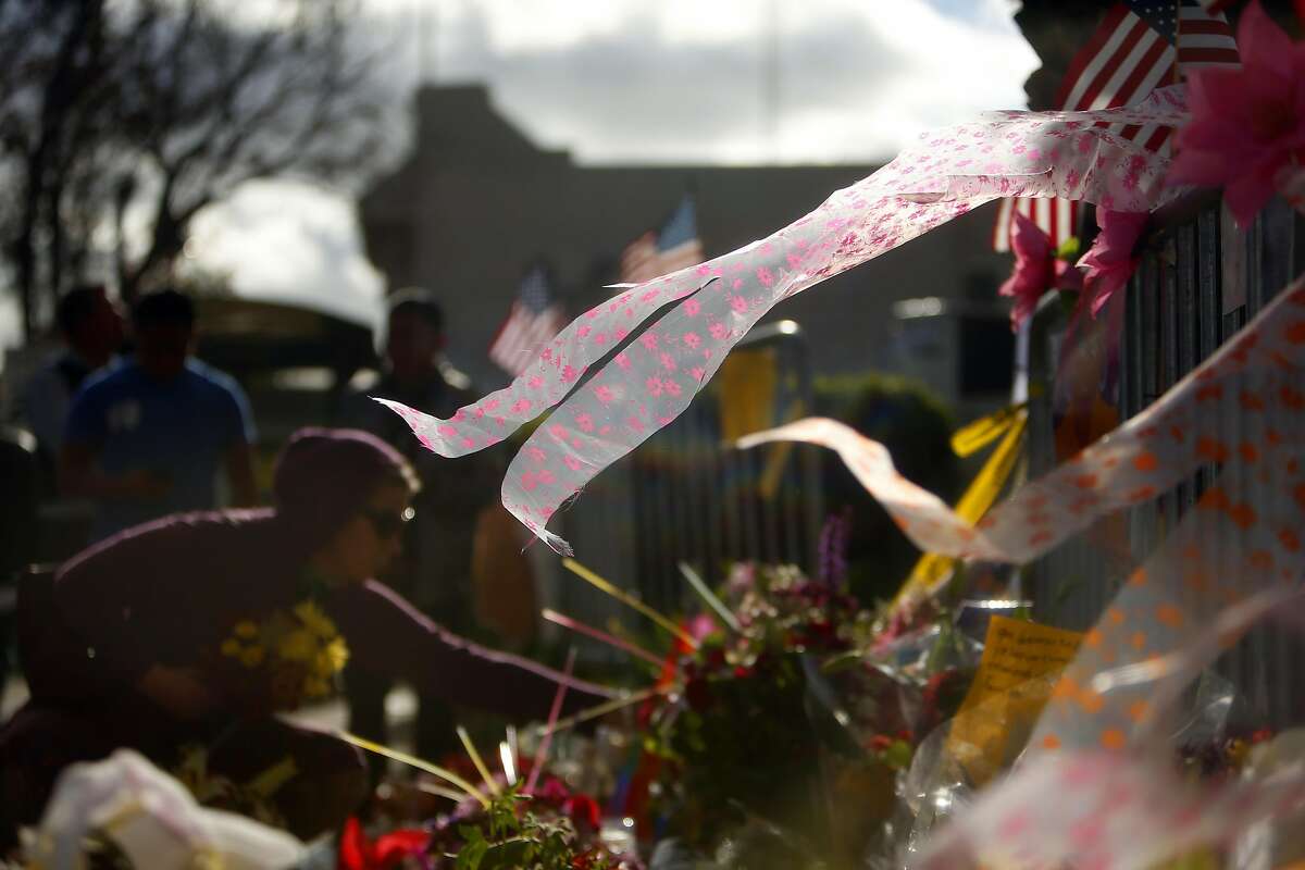 As the wind blows through a Fruitvale Avenue memorial, Tiffany Snow of Oakland places flowers in memory of her friend Griffin Madden who died in the Ghost Ship warehouse fire in Oakland, Calif., on Tuesday, December 6, 2016.