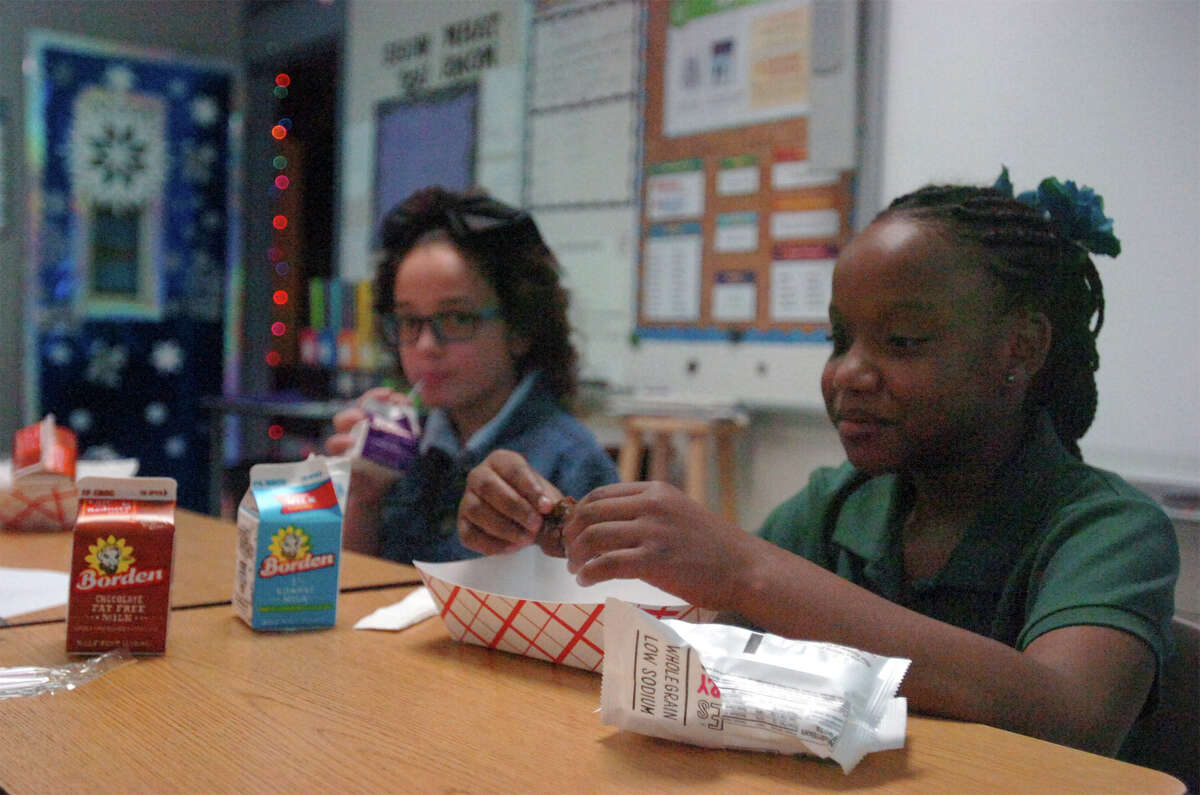 From left, Raylie Evans and Emonie Perkins eat breakfast before class starts at Newton Elementary Tuesday. The school began a new program that feeds all children breakfast in the classroom. Liz Teitz/The Enterprise.