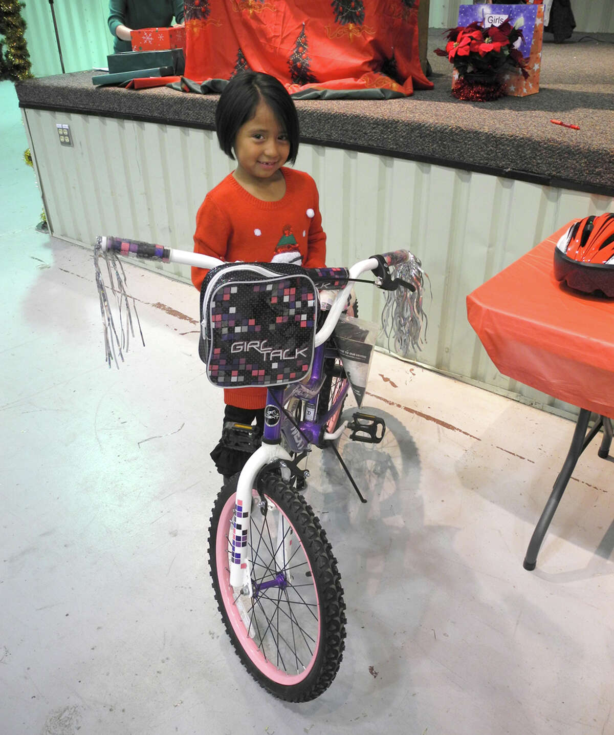 Annalyse Acosta, 7, waits to be fitted for a helmet before she takes home the new bike she won in a drawing at the Ollie Liner Center at Breakfast with Santa Saturday.
