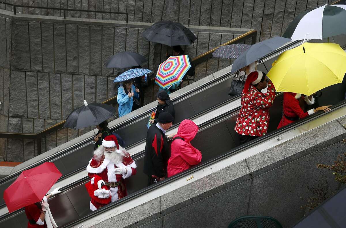 A Santa lookalike rides the escalator at Hallidie Plaza on his way to Union Square for the annual Santacon romp in San Francisco, Calif. on Saturday, Dec. 10, 2016.
