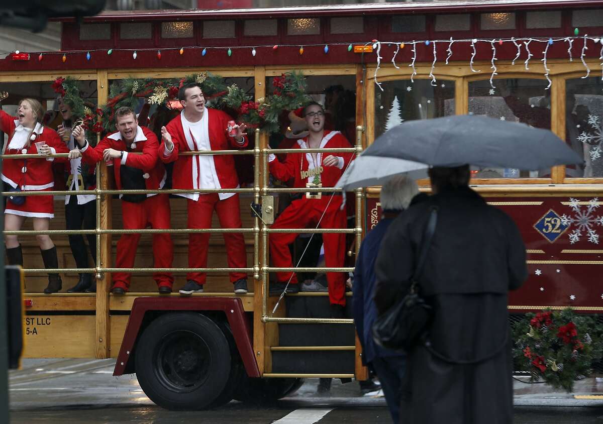 Partiers whoop it up aboard a motorized cable car circling Union Square for the annual Santacon romp in San Francisco, Calif. on Saturday, Dec. 10, 2016.