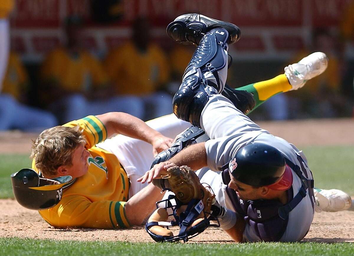 Oakland Athletics' Eric Byrnes, left, collides with Texas Rangers catcher Bill Haselman after being tagged out at home plate in the ninth inning Sunday, July 21, 2002, in Oakland, Calif. Byrnes was attempting to score from third on a fly ball by Mark Ellis. Texas won 7-3 in 12 innings. The Rangers wer wearing the uniforms of the 1961 Washington Senators, while the Athletics were wearing those of the 1972 world champion Athletics. (AP Photo/Ben Margot)