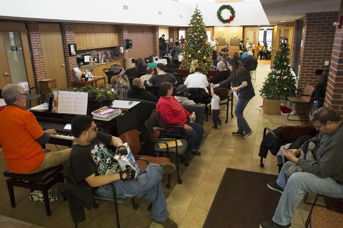 Participants wait their turn in a lobby while volunteer David Moll, of Midland, plays Christmas songs on a piano during a free dental clinic sponsored by Midland Seventh-day Adventist Church at the Midland Community Center on Sunday.