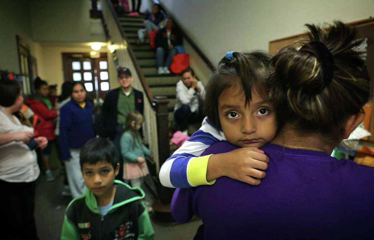 Ashley Rivas, 4, looks over the shoulder of her mother Griselda Rivas, 30, of El Salvador, after arriving at the San Antonio Mennonite Church where hundreds of immigrants from Central America have been dropped off by ICE. Volunteers mentioned they went out to buy blankets and air mattresses, and the last bus dropped off another group at 3 A.M. on Monday, Dec. 5, 2016.