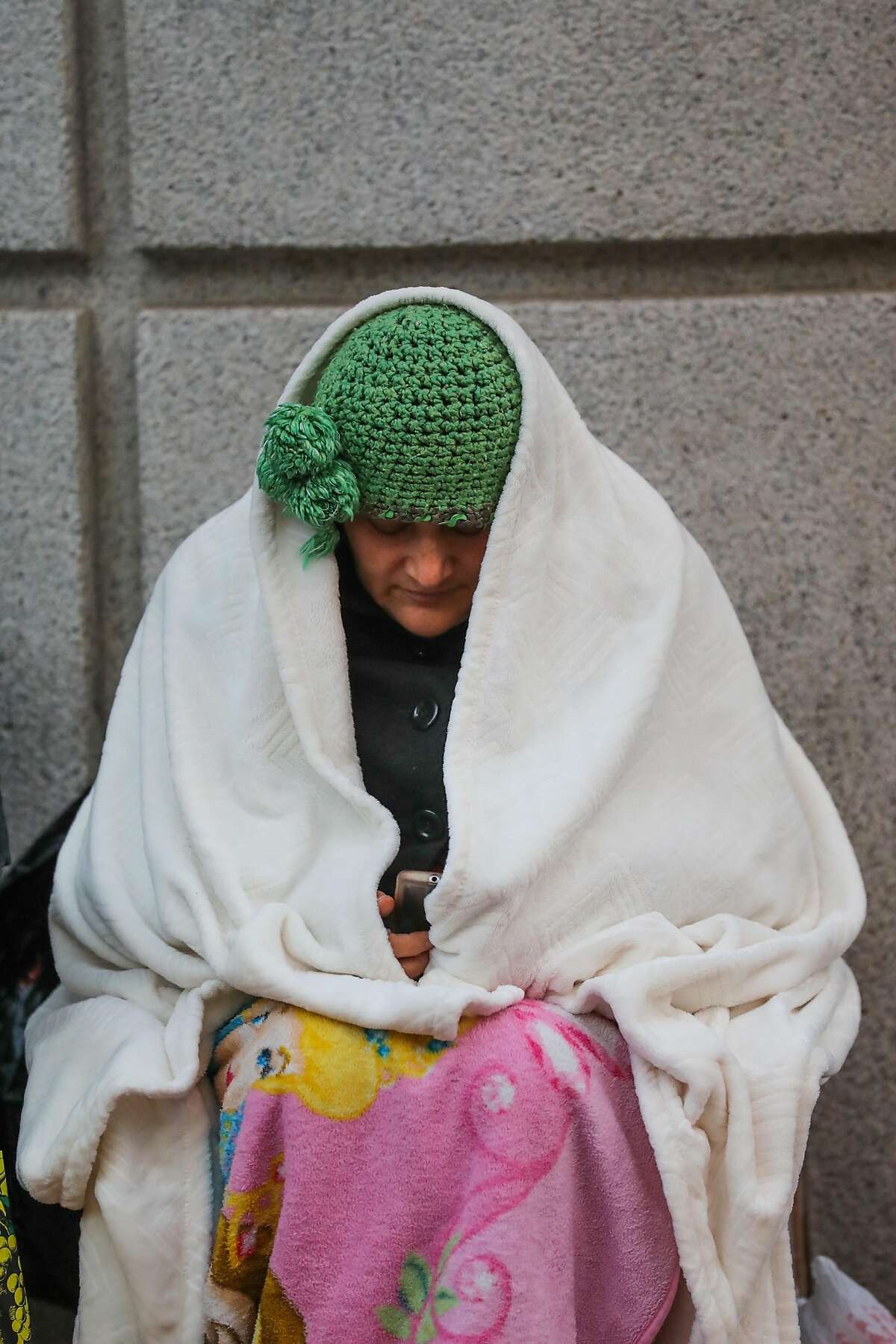 Maria Lopez, who camped out overnight, bundles up as she sits on Market Street, waiting for Hamilton tickets to go on sale, in San Francisco, California, on Monday, Dec. 12, 2016.